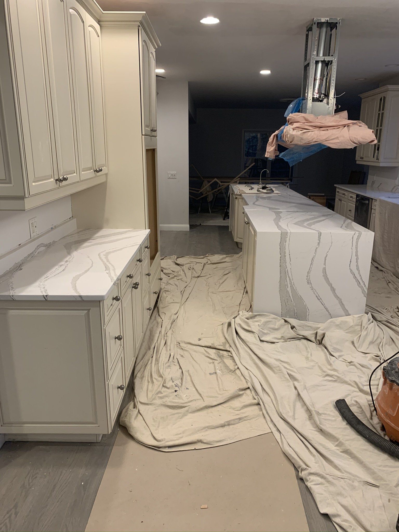 A kitchen is being remodeled with white cabinets and marble counter tops.