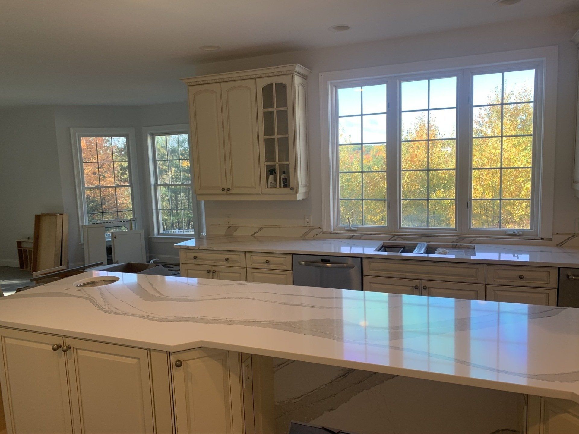 A kitchen with white cabinets , white counter tops , a sink , and a large island.
