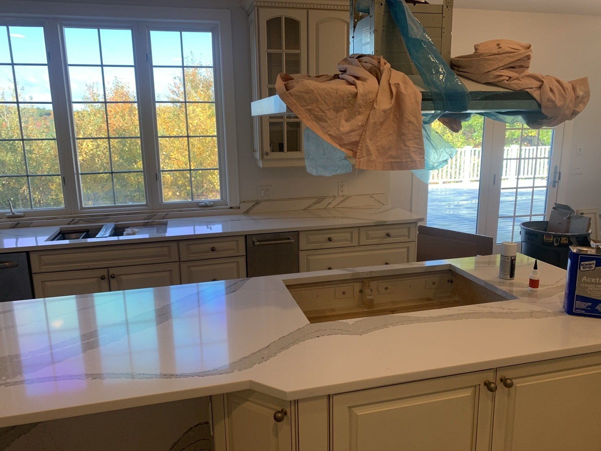 A kitchen with white cabinets , a sink , and a window.