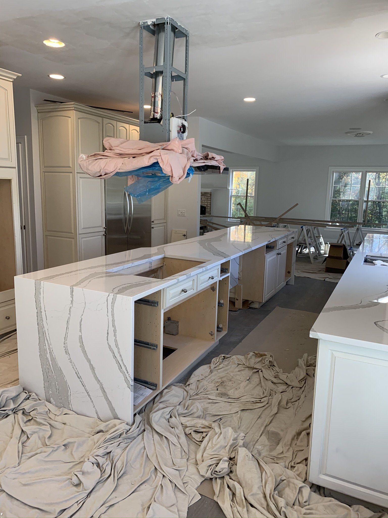 A kitchen under construction with white cabinets and marble counter tops.