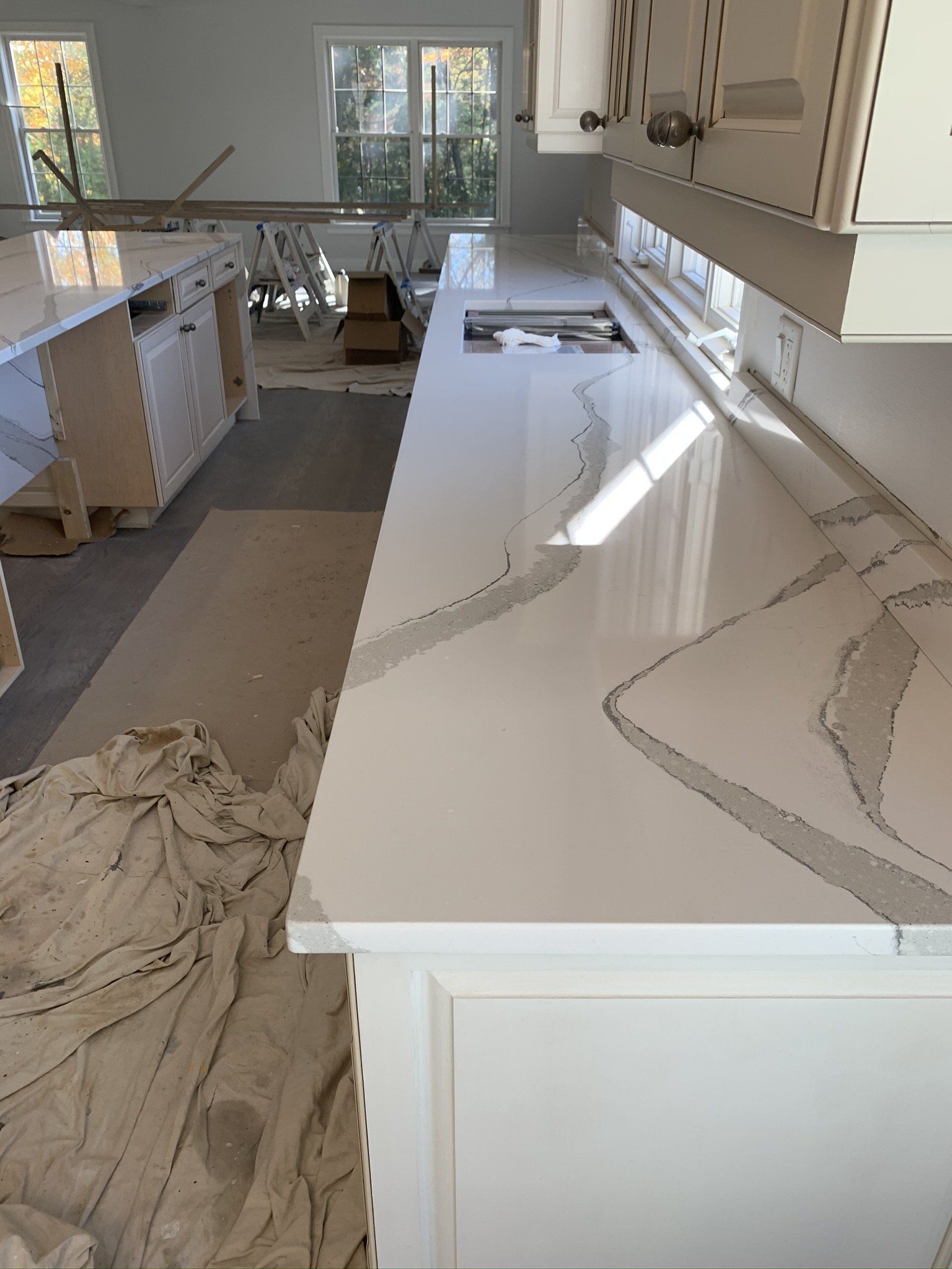 A kitchen with white cabinets and white counter tops is being remodeled.