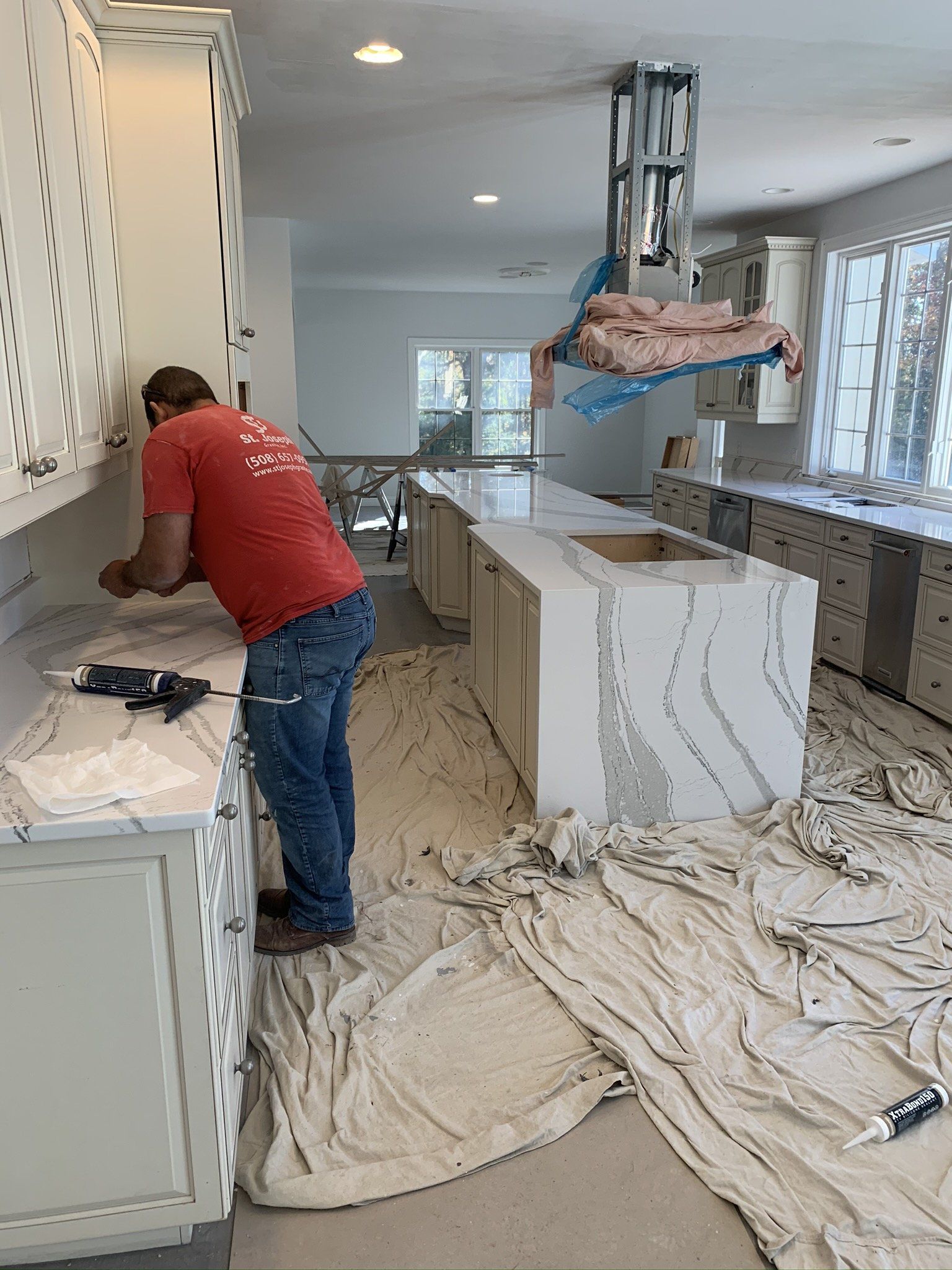 A man in a red shirt is working on a kitchen counter.