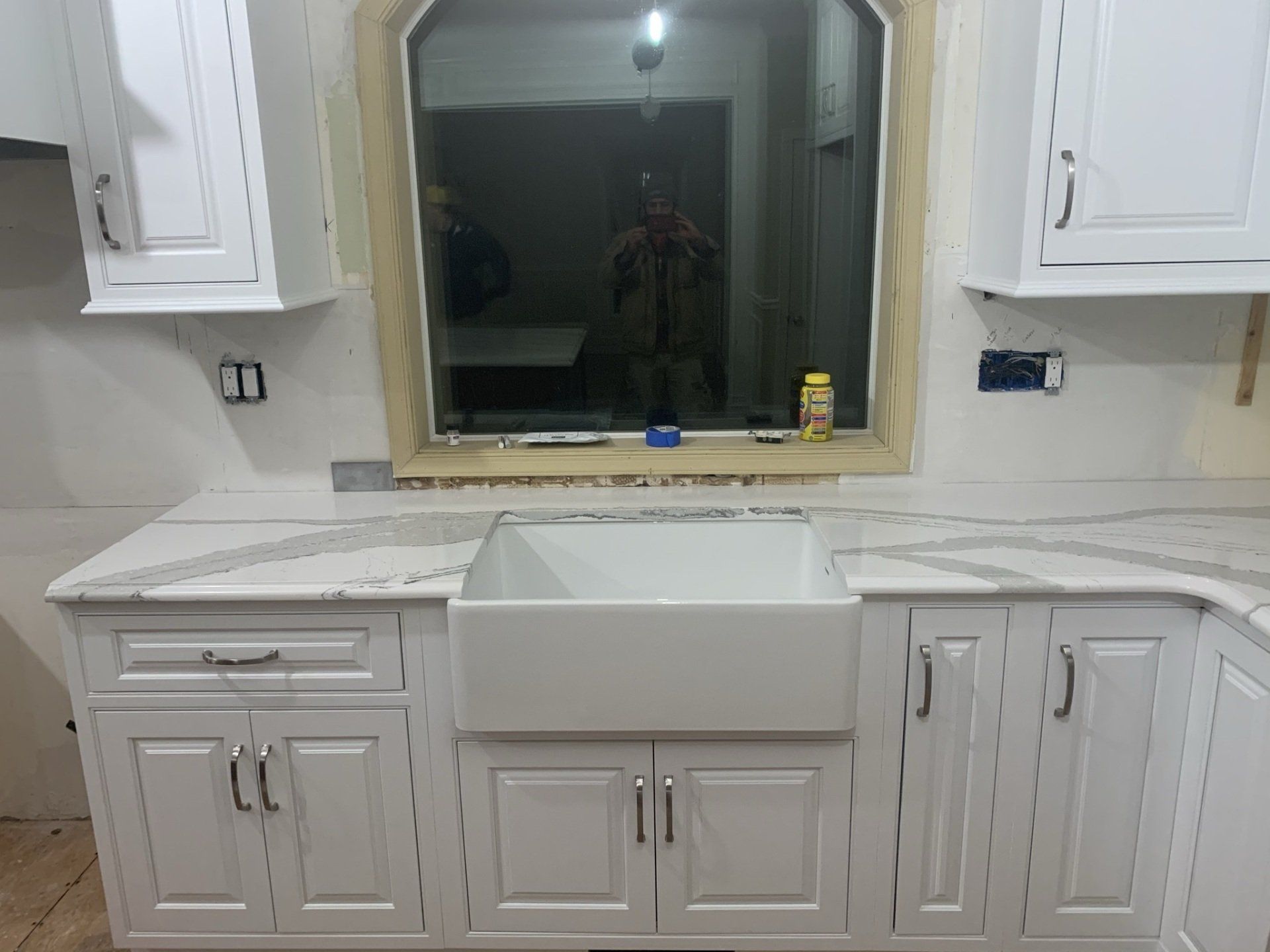 A kitchen with white cabinets and a white sink.