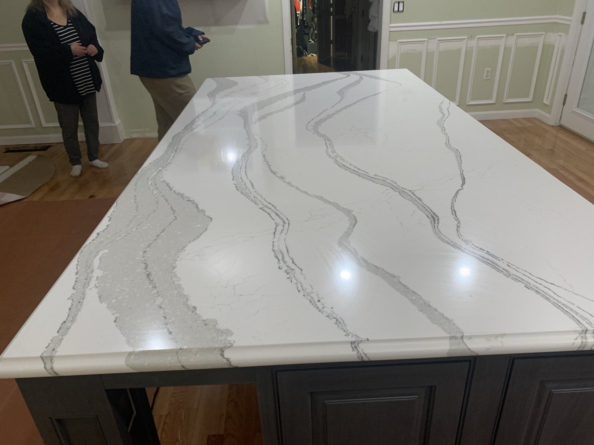 A man and woman are standing next to a large white counter top in a kitchen.