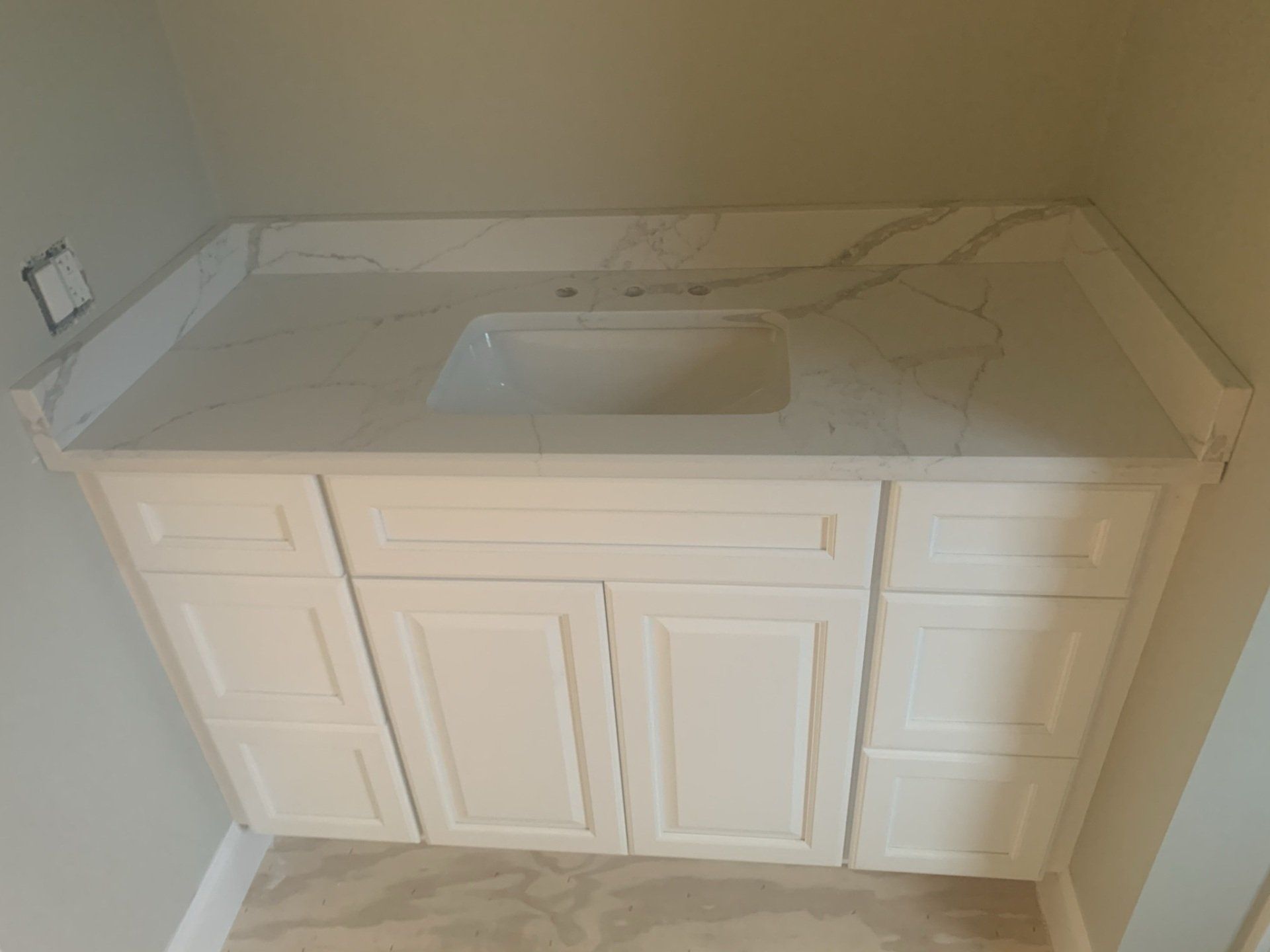 A bathroom vanity with white cabinets and a sink.
