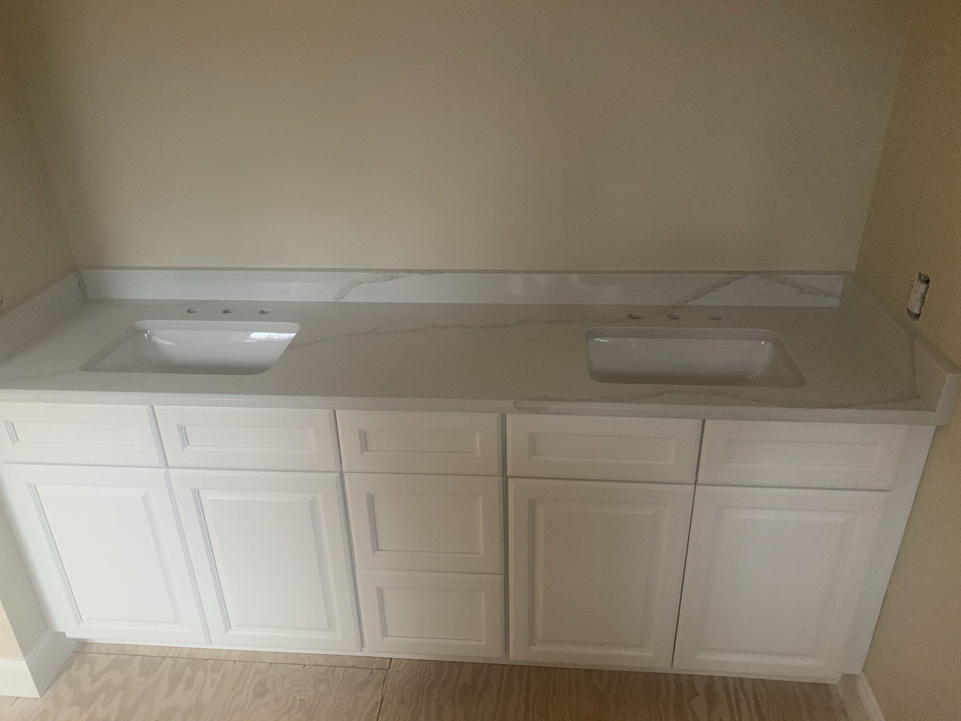 A bathroom vanity with two sinks and white cabinets.