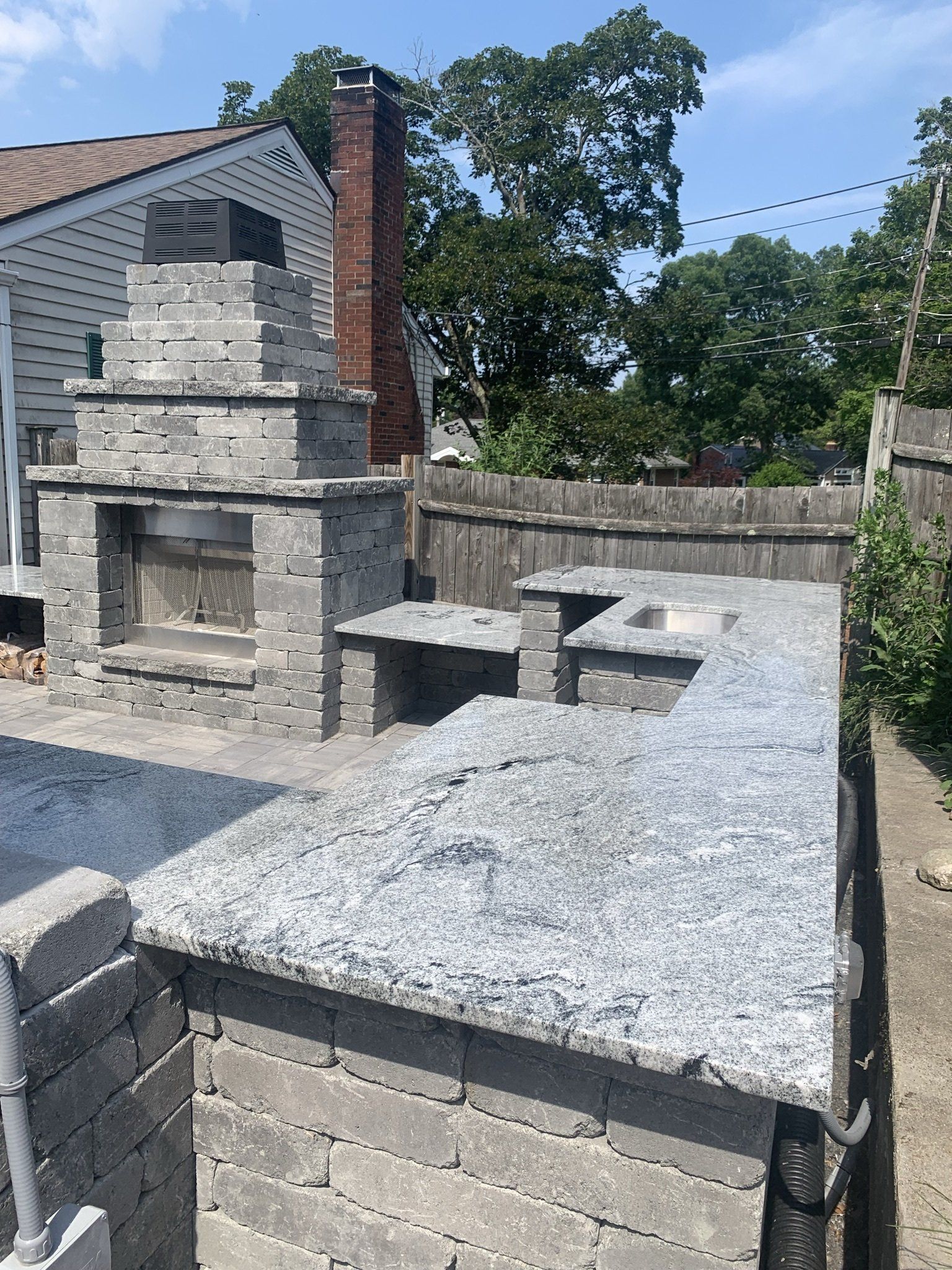 A brick fireplace is being built in the backyard of a house.