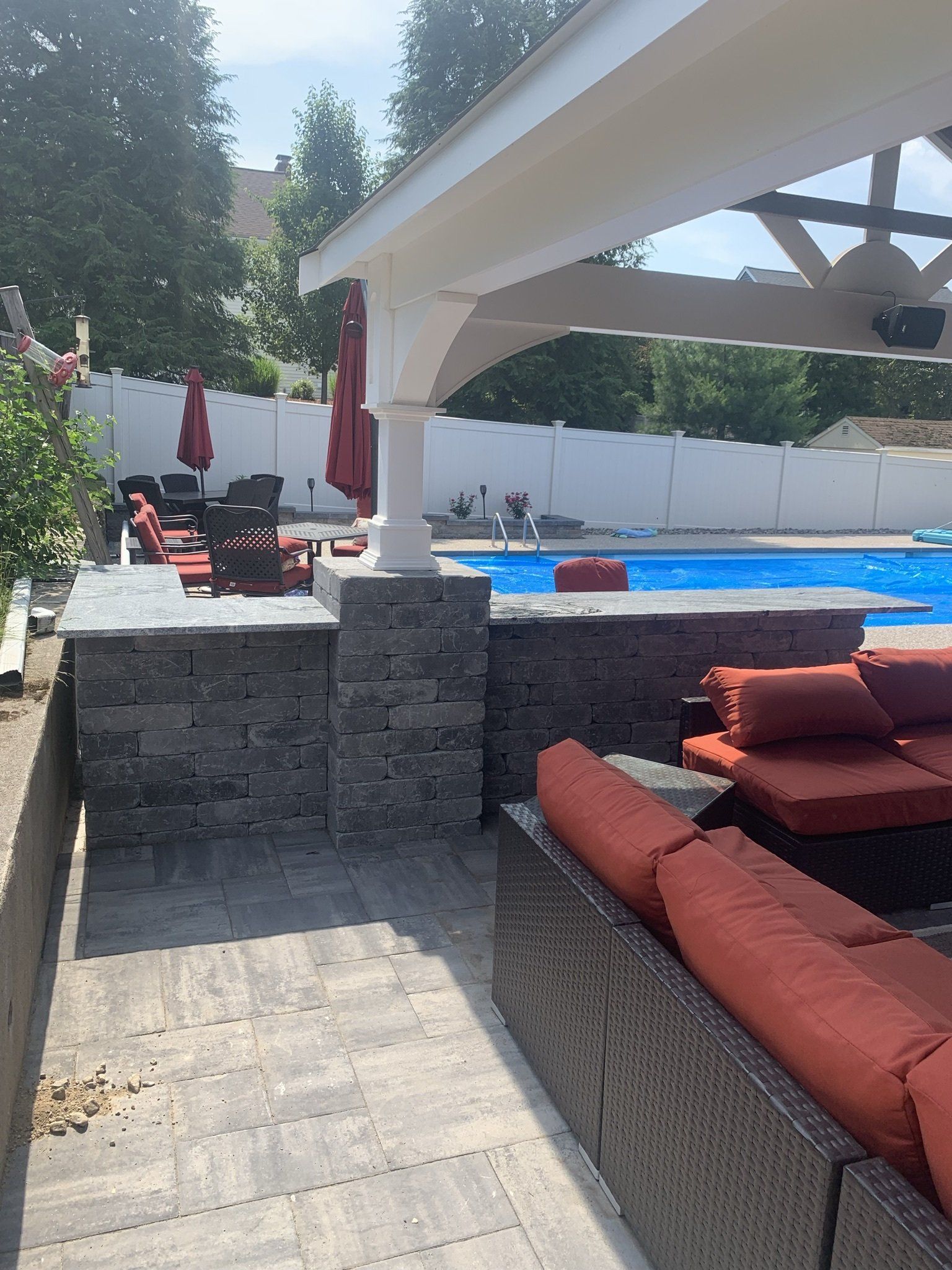 A patio with a couch and chairs next to a pool.
