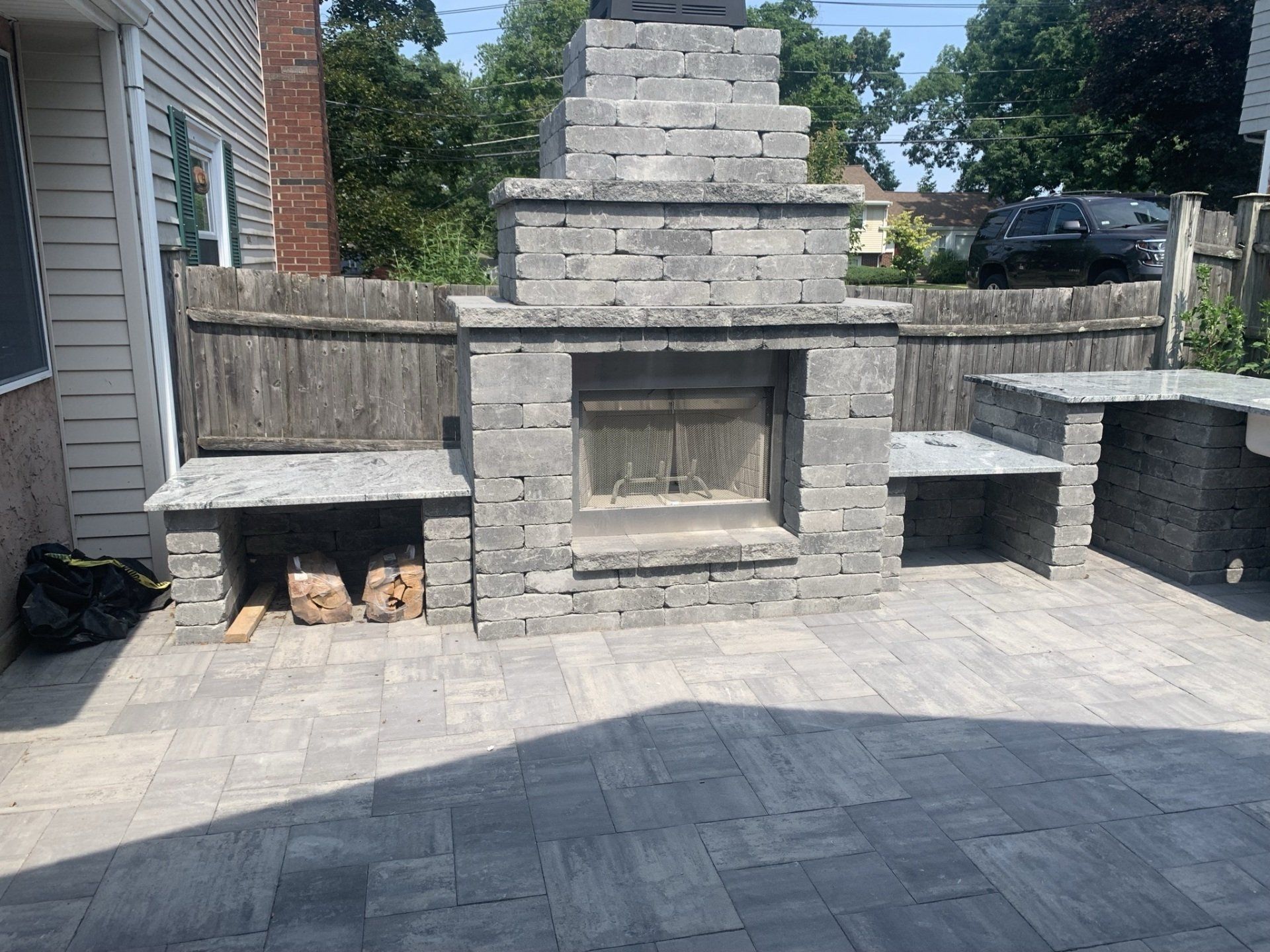 A brick fireplace on a patio with a wooden fence in the background