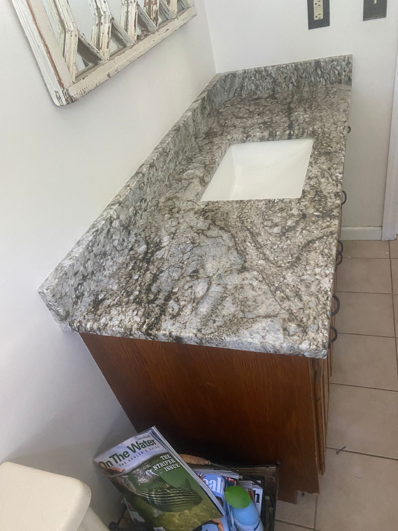 A bathroom vanity with a granite counter top and a sink.