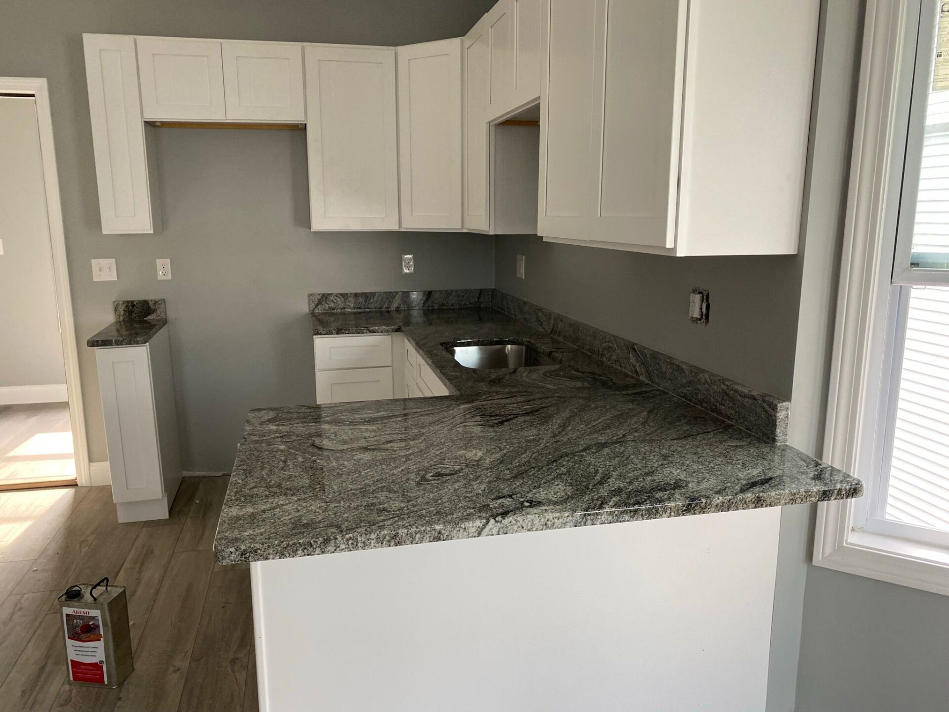 A kitchen with granite counter tops and white cabinets.