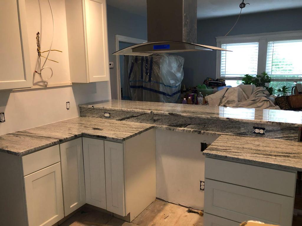 A kitchen with white cabinets and granite counter tops is being remodeled.