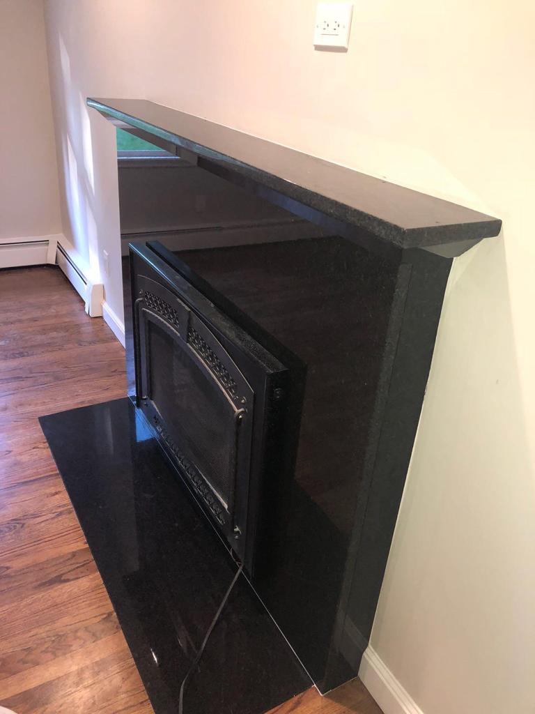 A black fireplace with a microwave inside of it in a living room.