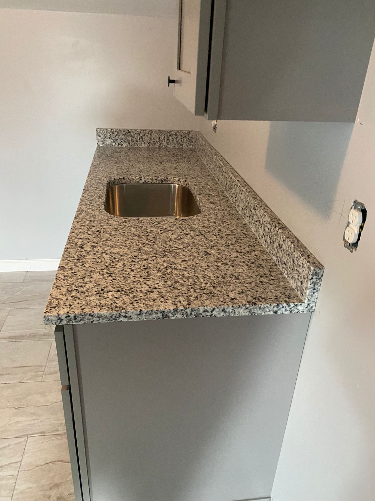 A kitchen with a granite counter top and a stainless steel sink.