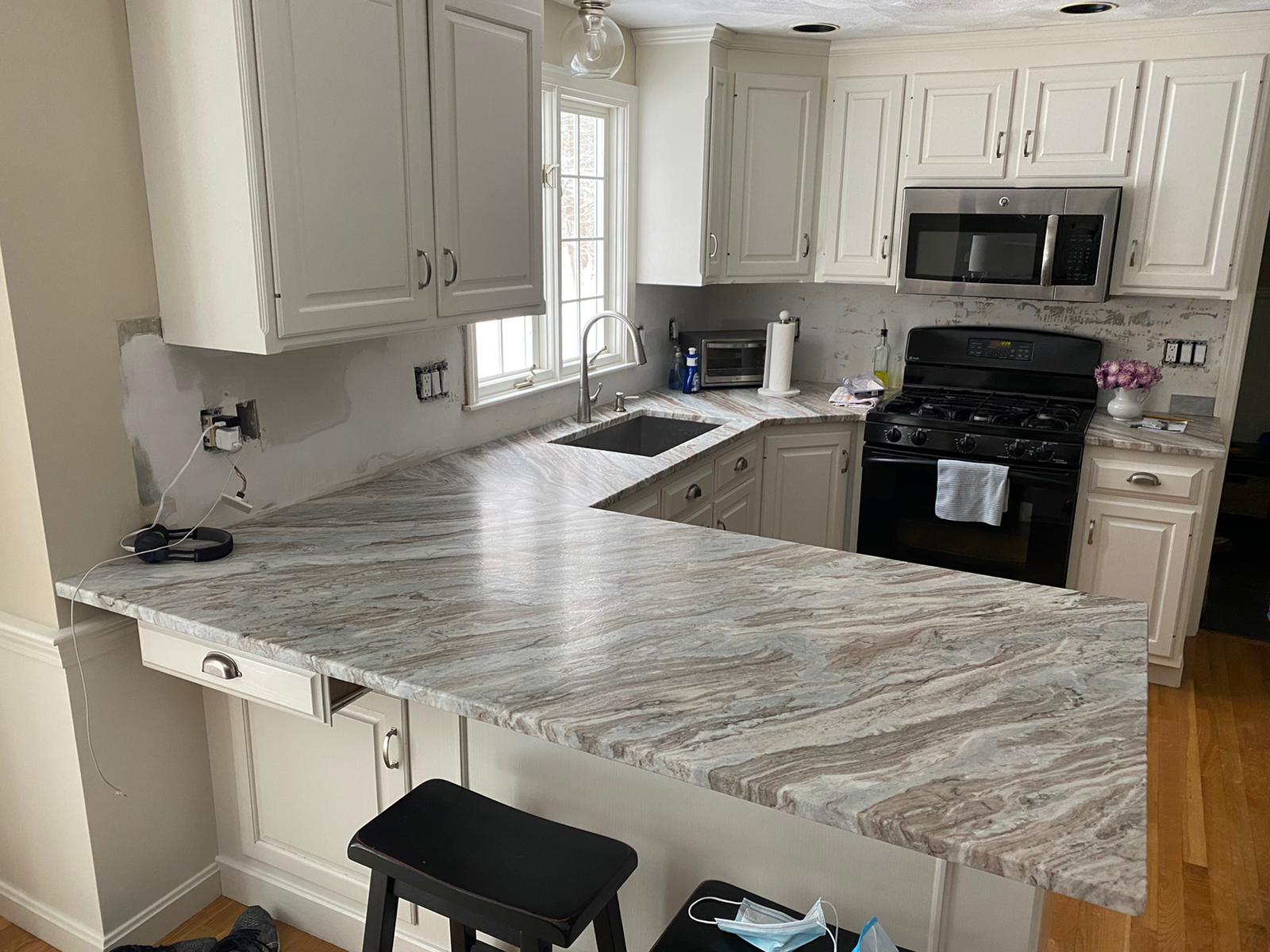 A kitchen with white cabinets and granite counter tops.