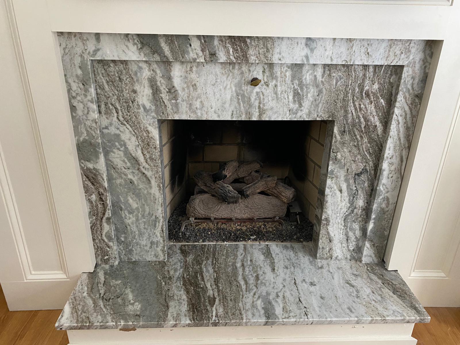 A fireplace with a marble surround and a wood burner in it.