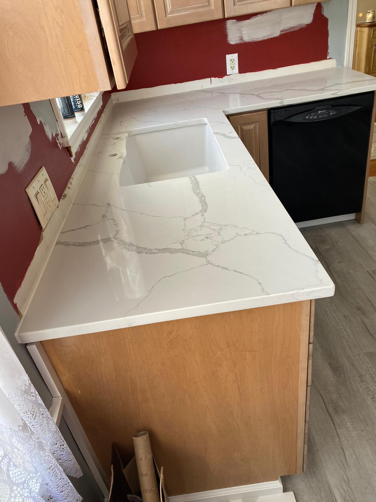 A kitchen with a white counter top and a sink.