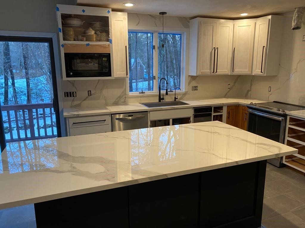 A kitchen with white cabinets and a large island in the middle.