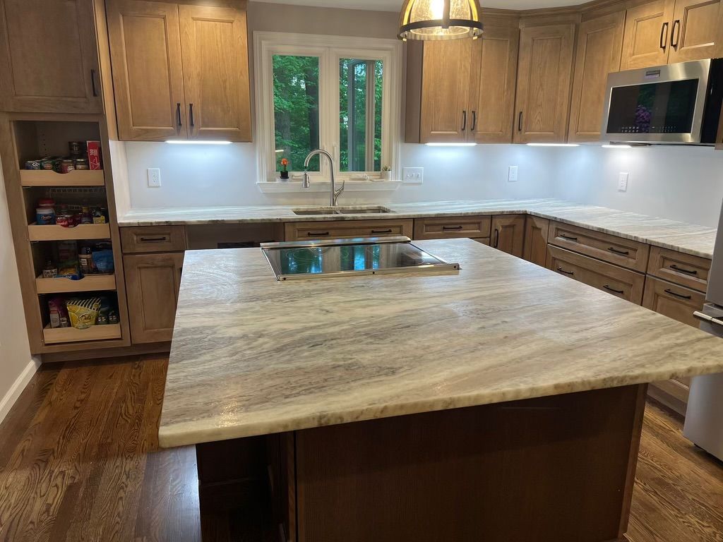 A kitchen with wooden cabinets , granite counter tops , stainless steel appliances and a large island.