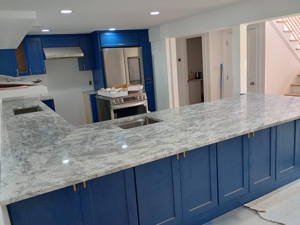 A kitchen with blue cabinets and white granite counter tops.