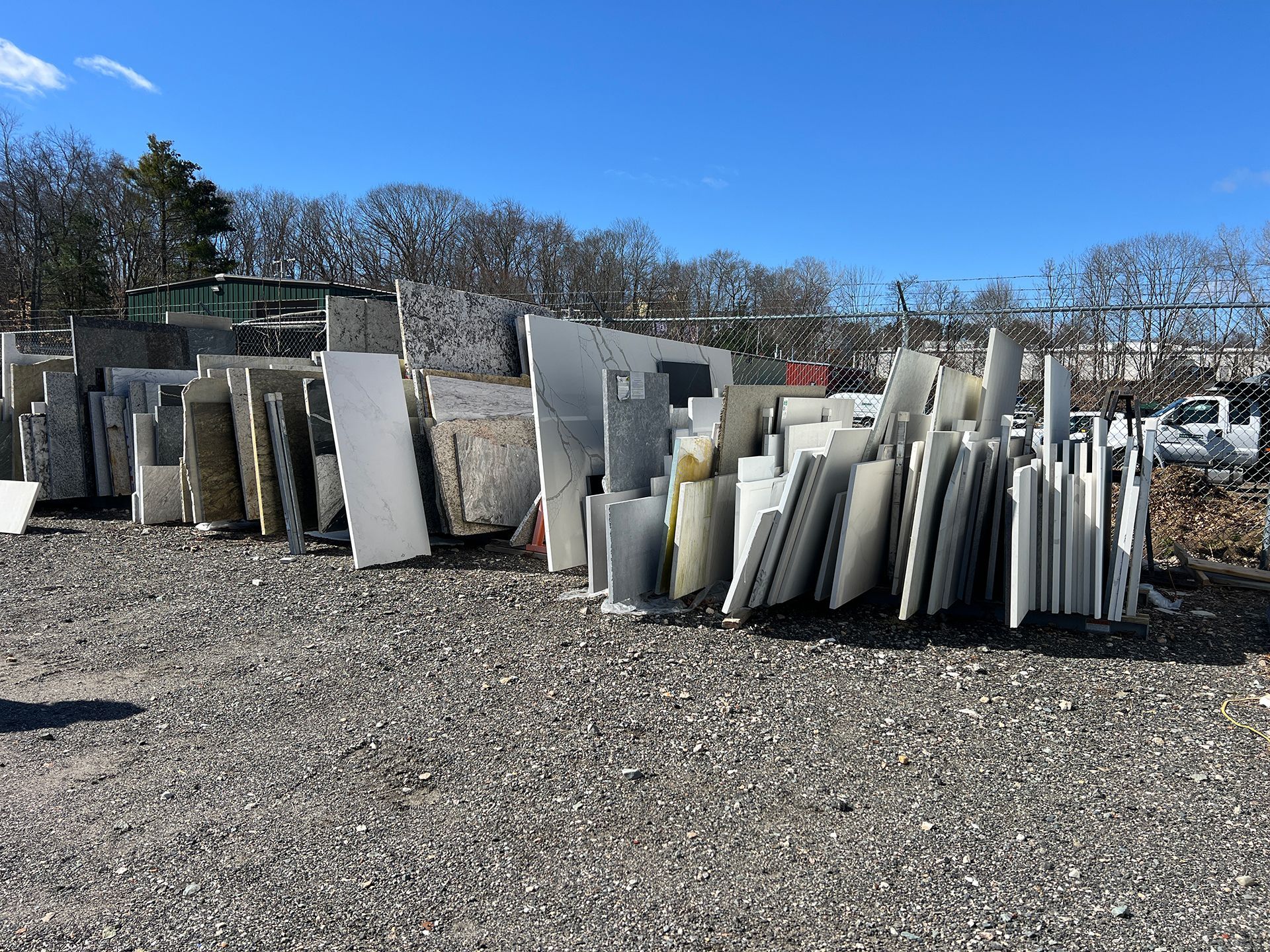 A pile of marble slabs are stacked on top of each other in a gravel yard.