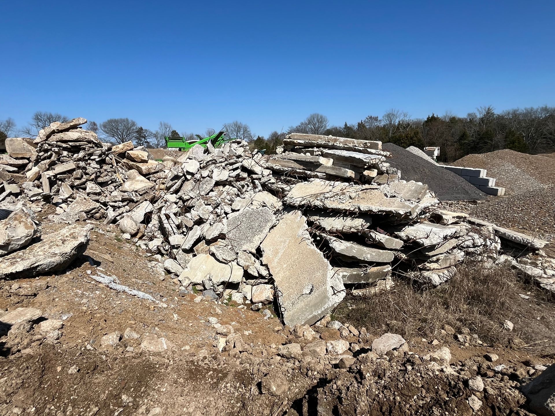 Pile of broken concrete and rubble at a demolition site under a clear blue sky.