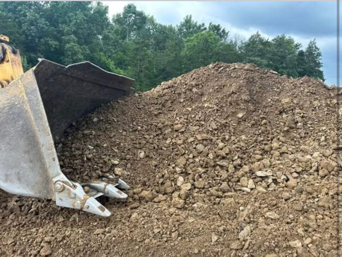 Bulldozer bucket next to a large pile of gravel at a construction site