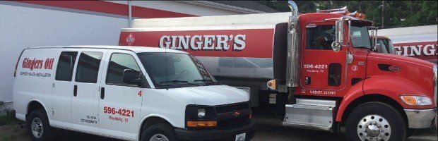 A white van is parked next to a red truck that says ginger 's