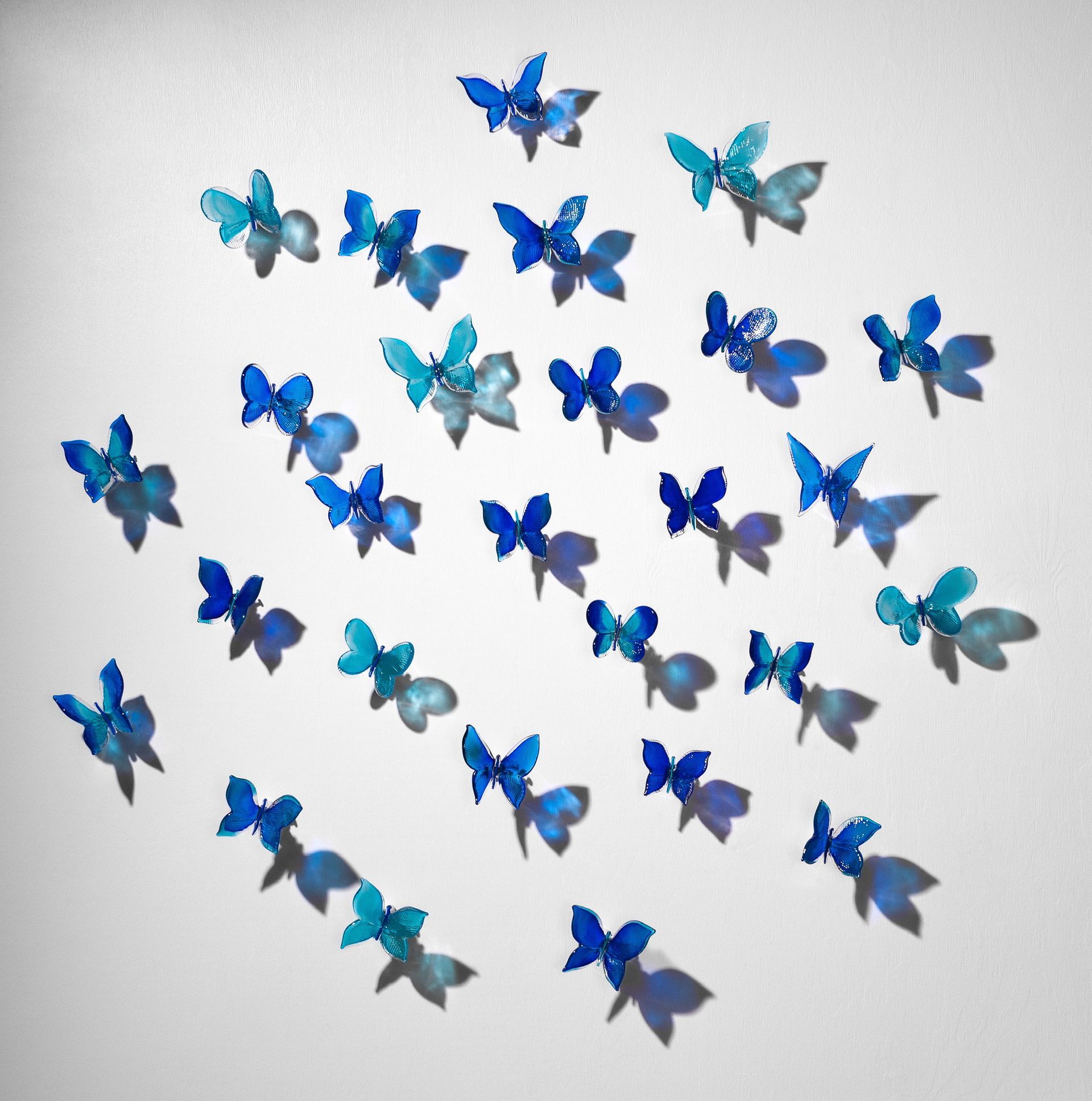 Blue butterflies arranged in a diagonal cluster on a light gray background