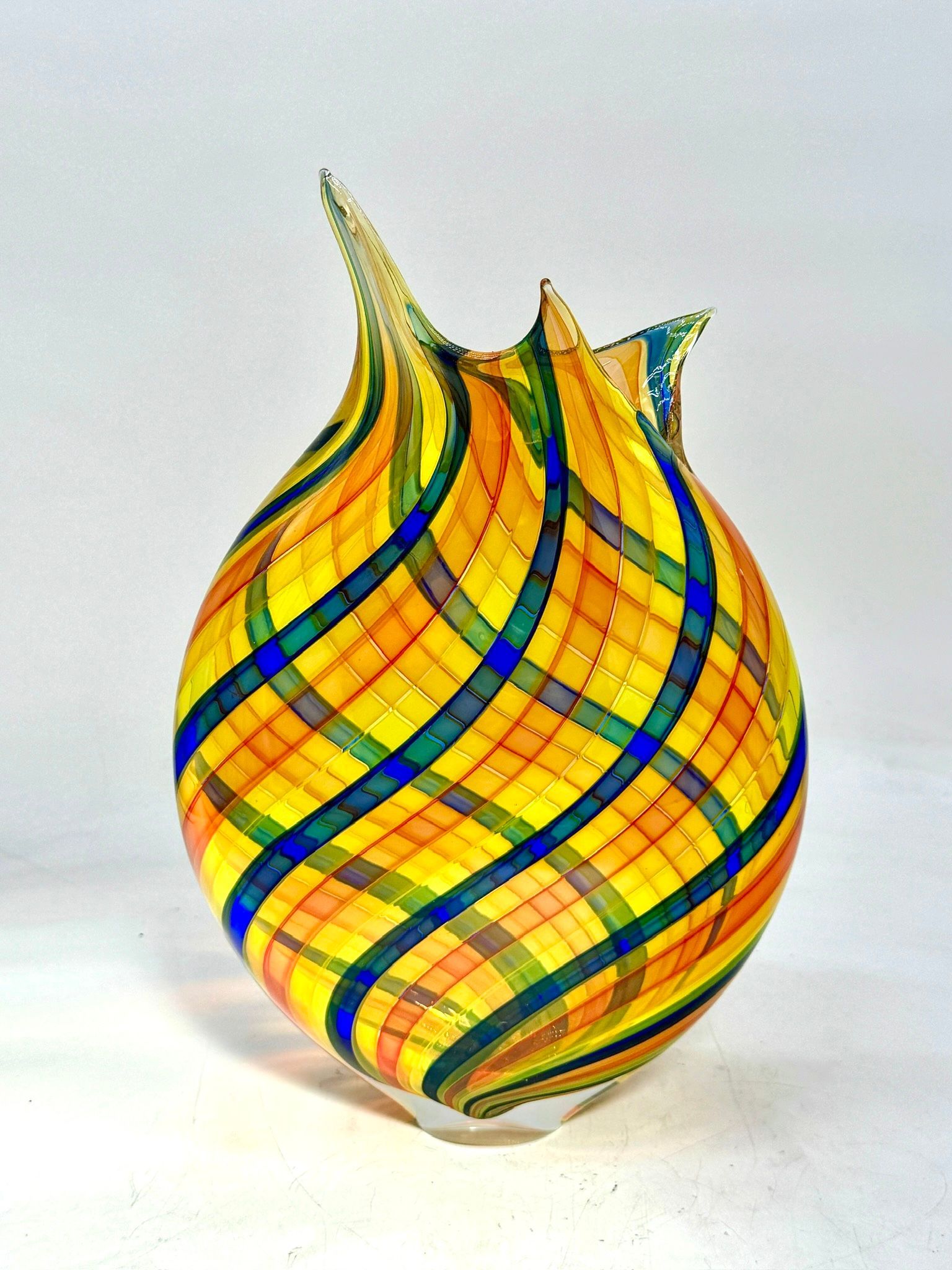 Colorful striped glass vase with a flared, flame-like top on a white background