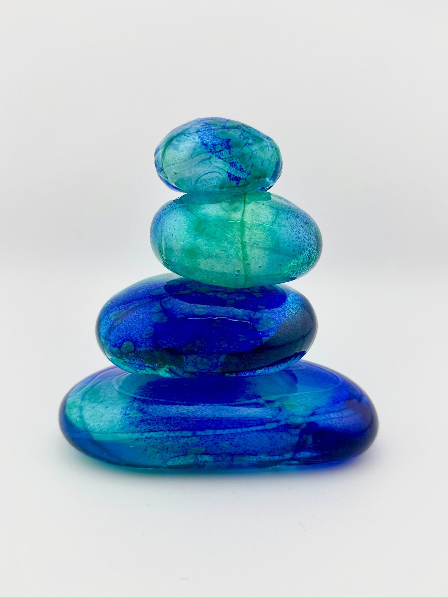 Stacked blue and green glass stones on a white background