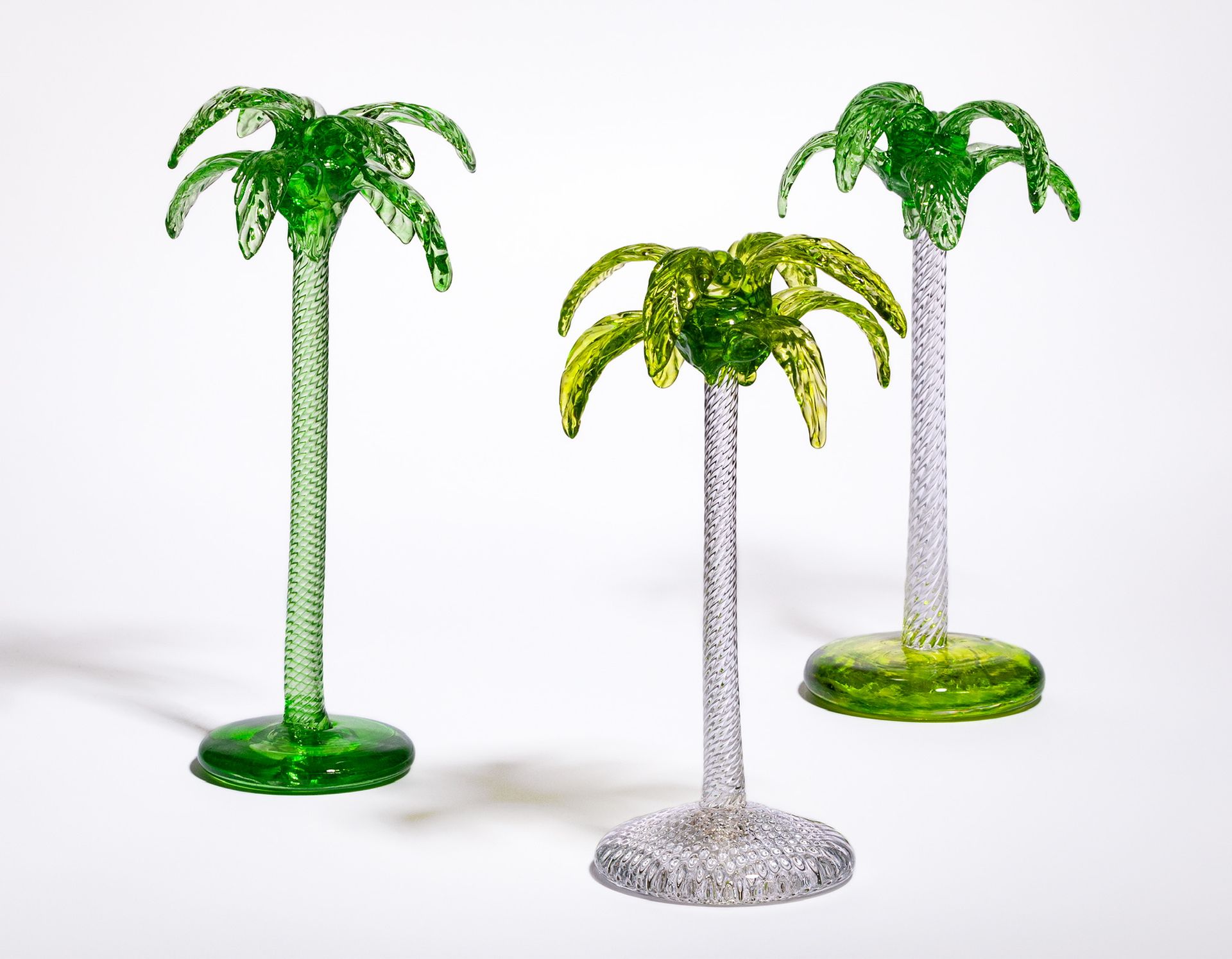 Three decorative palm-shaped objects in green, yellow, and silver on a white background