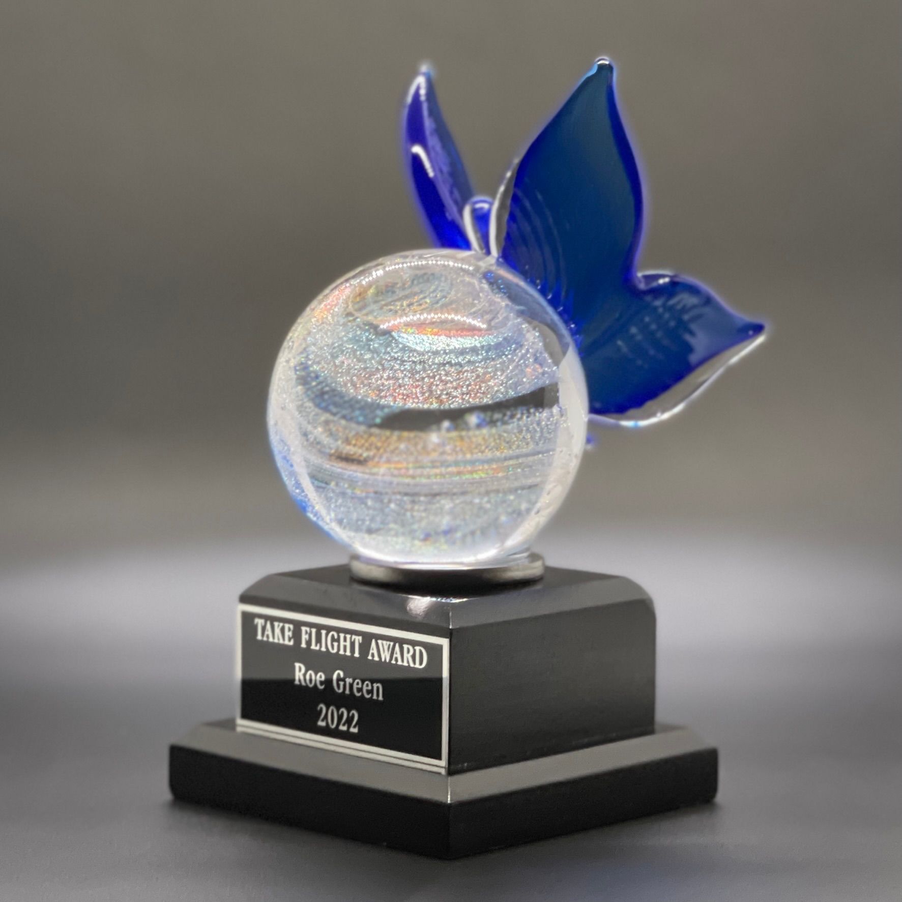 Glass award trophy with blue wings on a black base, engraved with “Tail Flight Award” and “2022”
