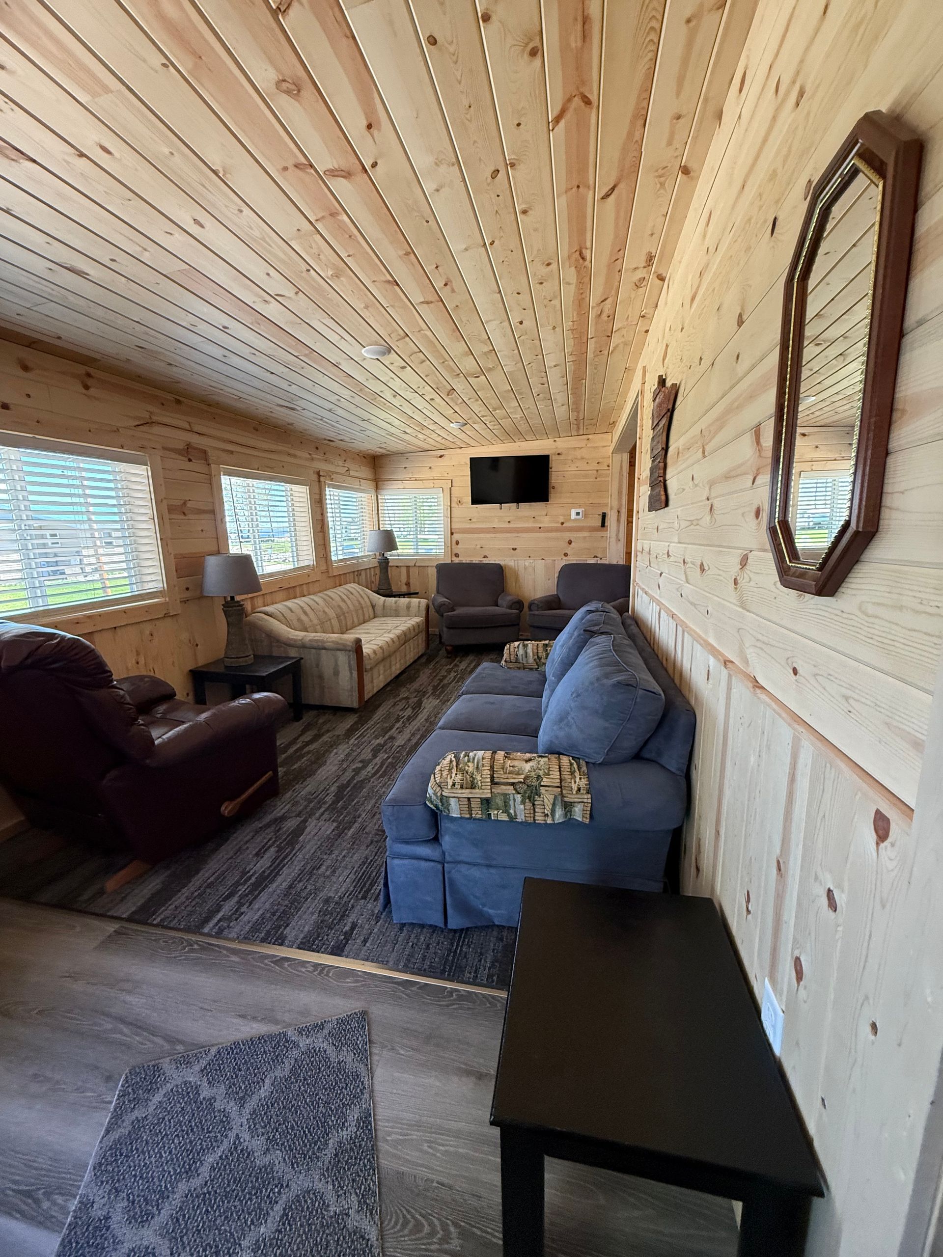 A living room with a couch , chair , table and mirror.