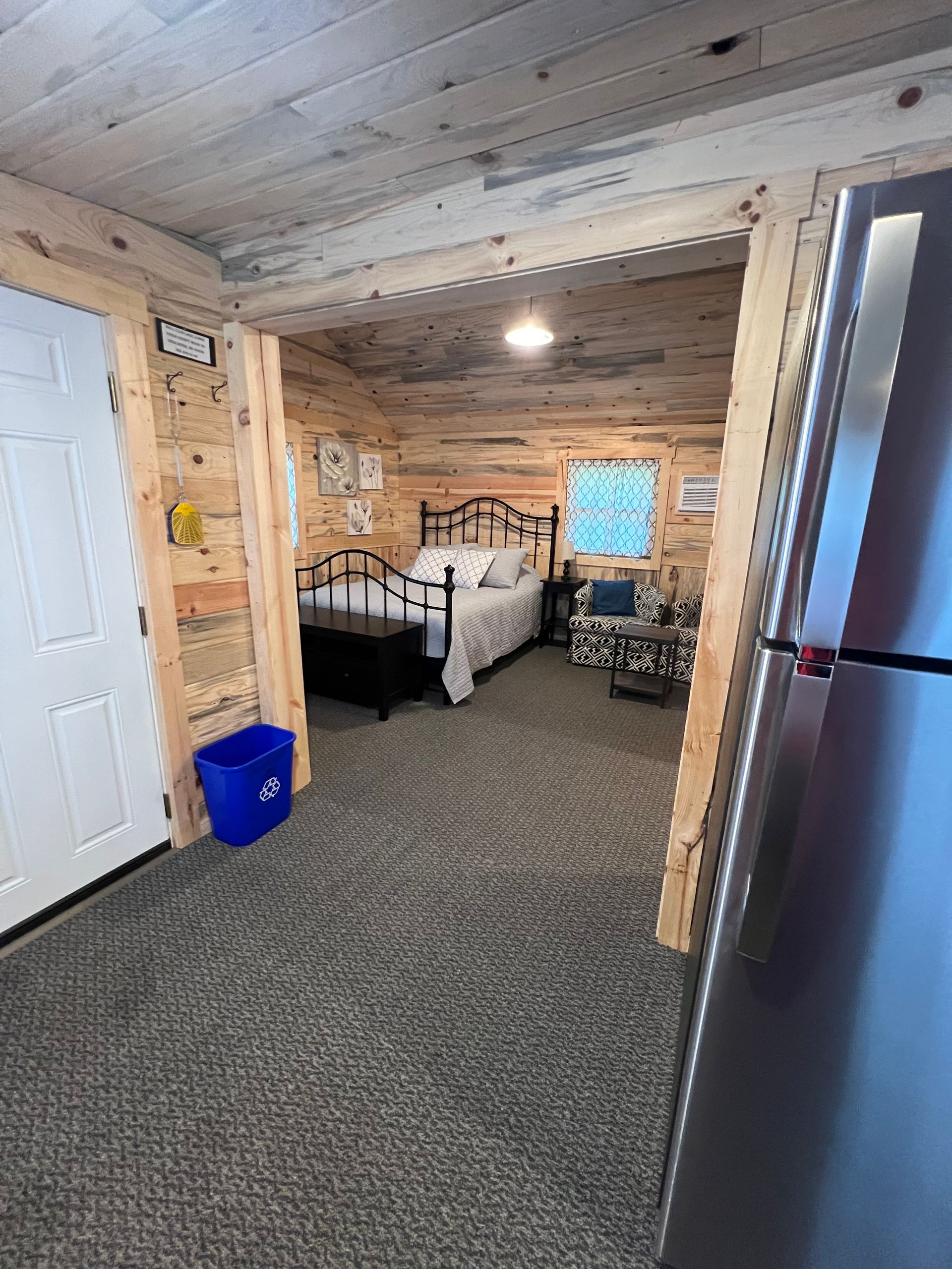 A bedroom in a log cabin with a bed and a refrigerator.