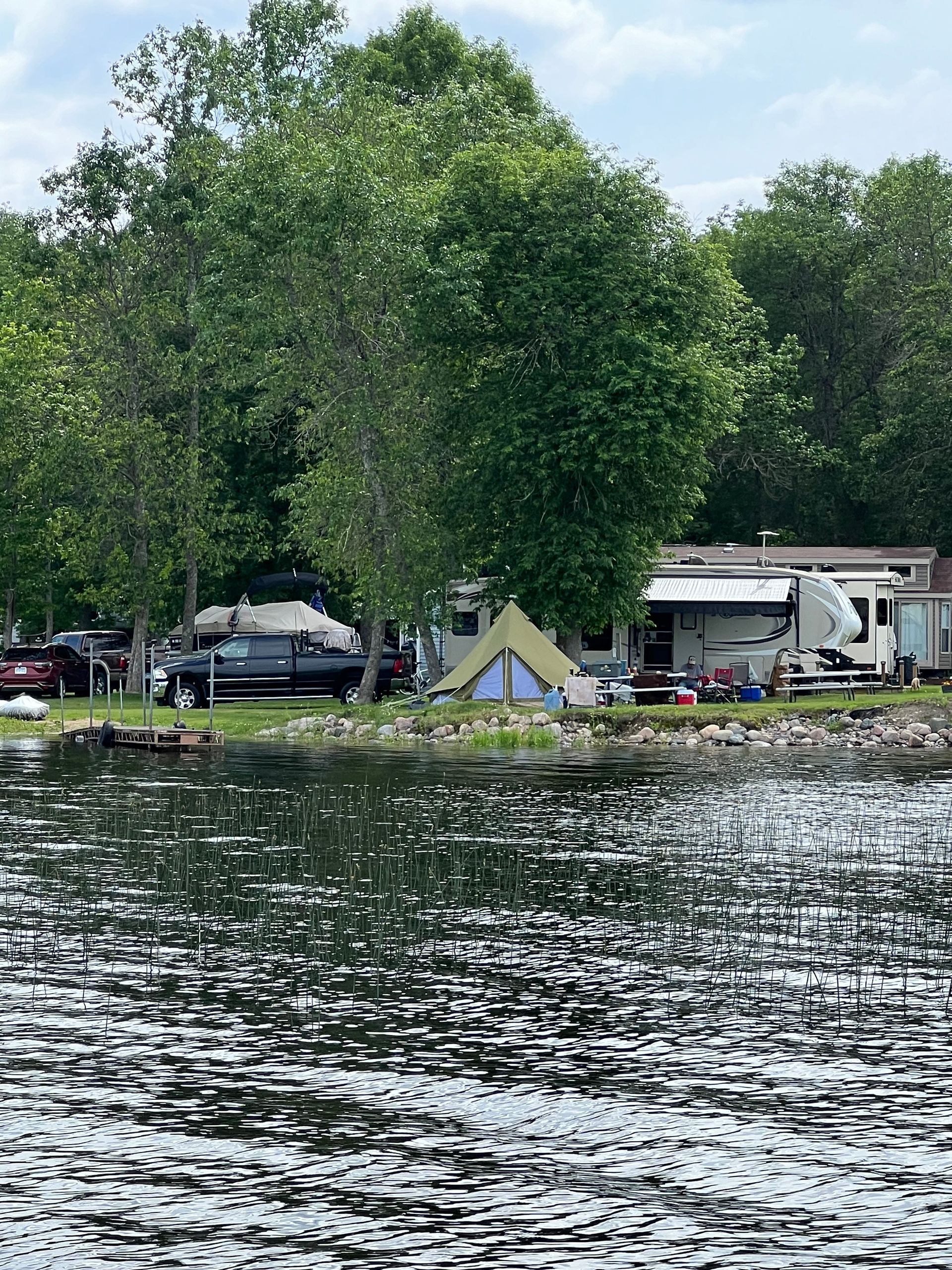 A group of tents are sitting on the shore of a lake.