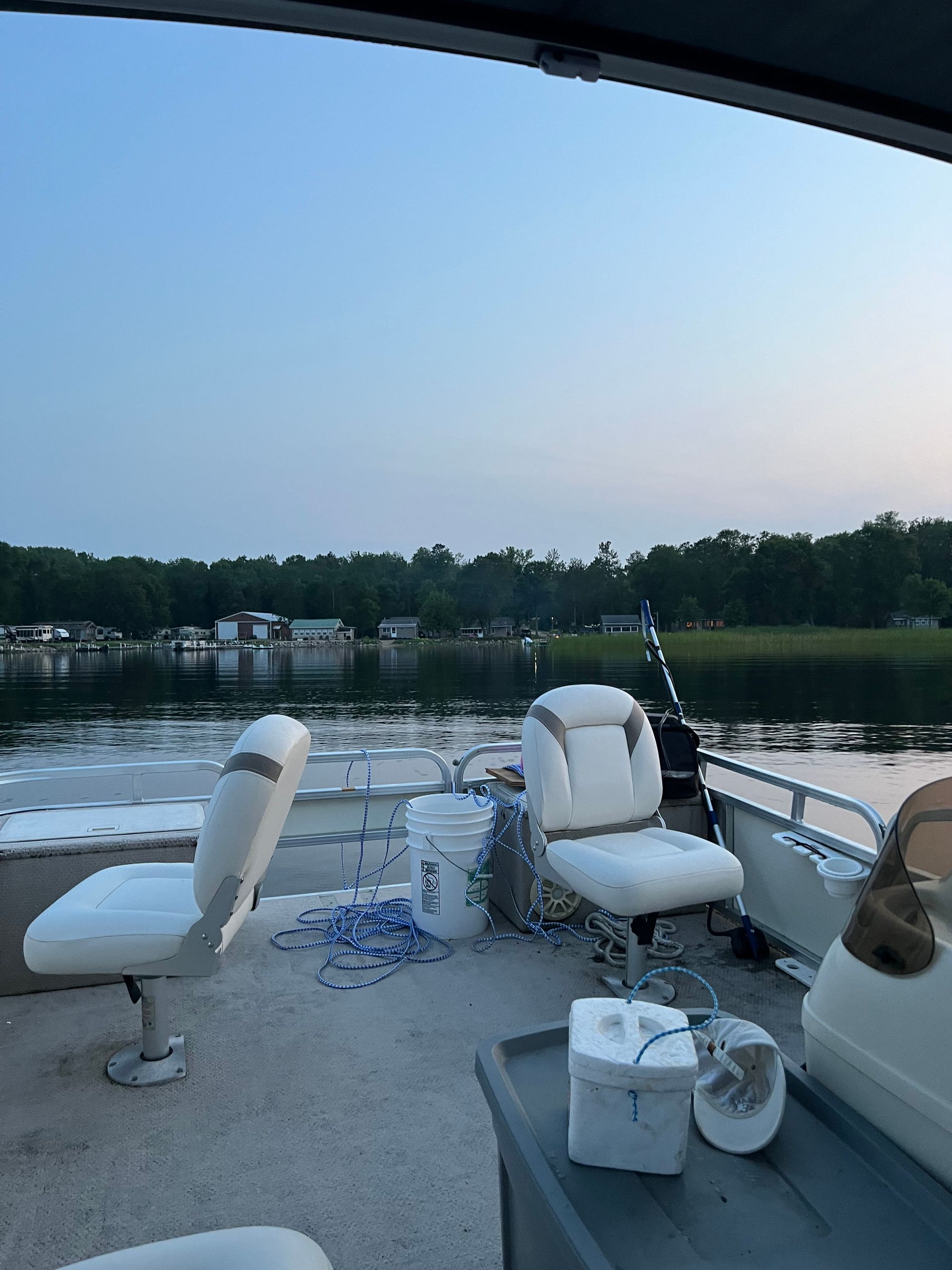 A pontoon boat is sitting on the shore of a lake