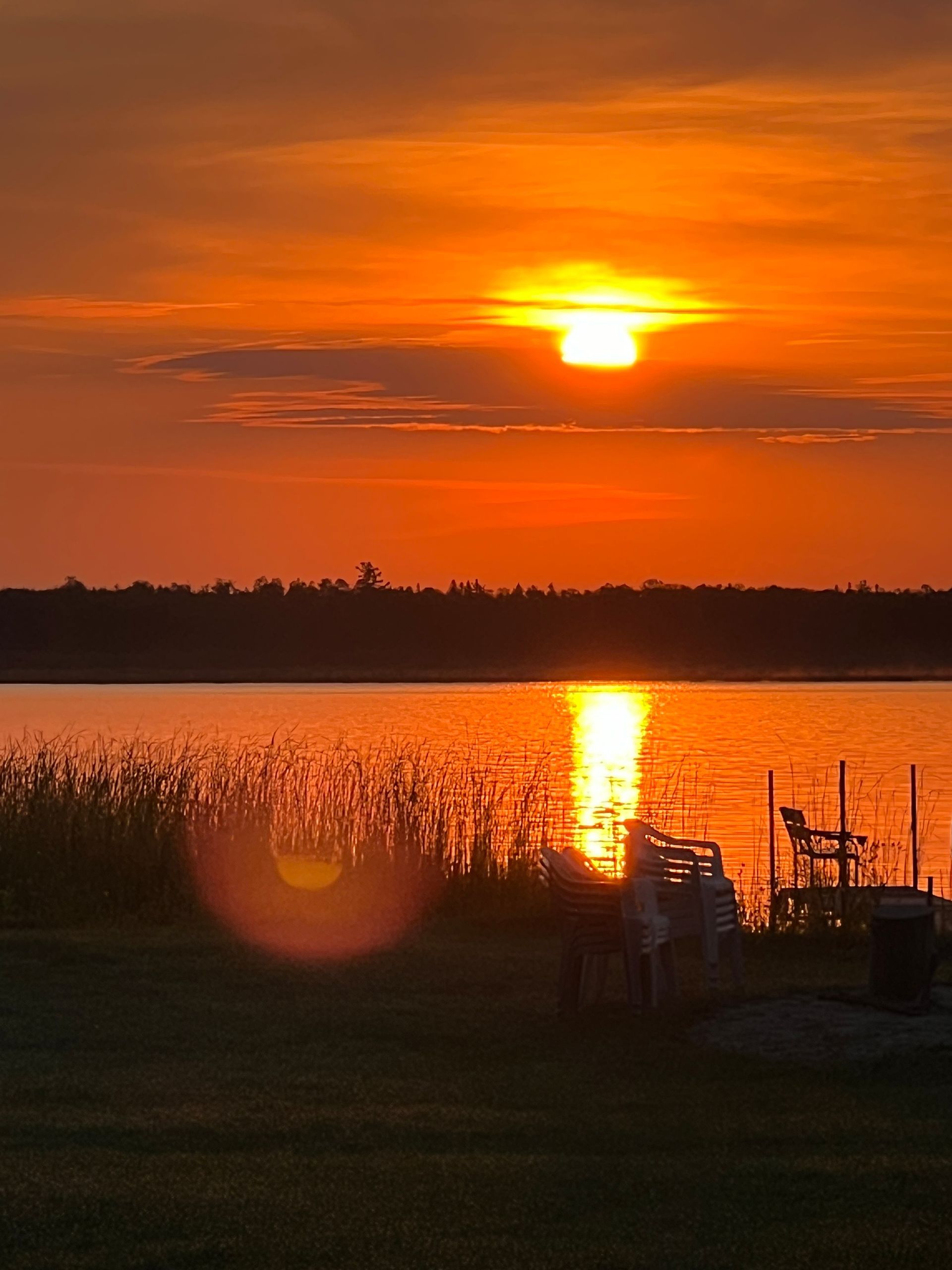A sunset over a lake with a dock in the foreground