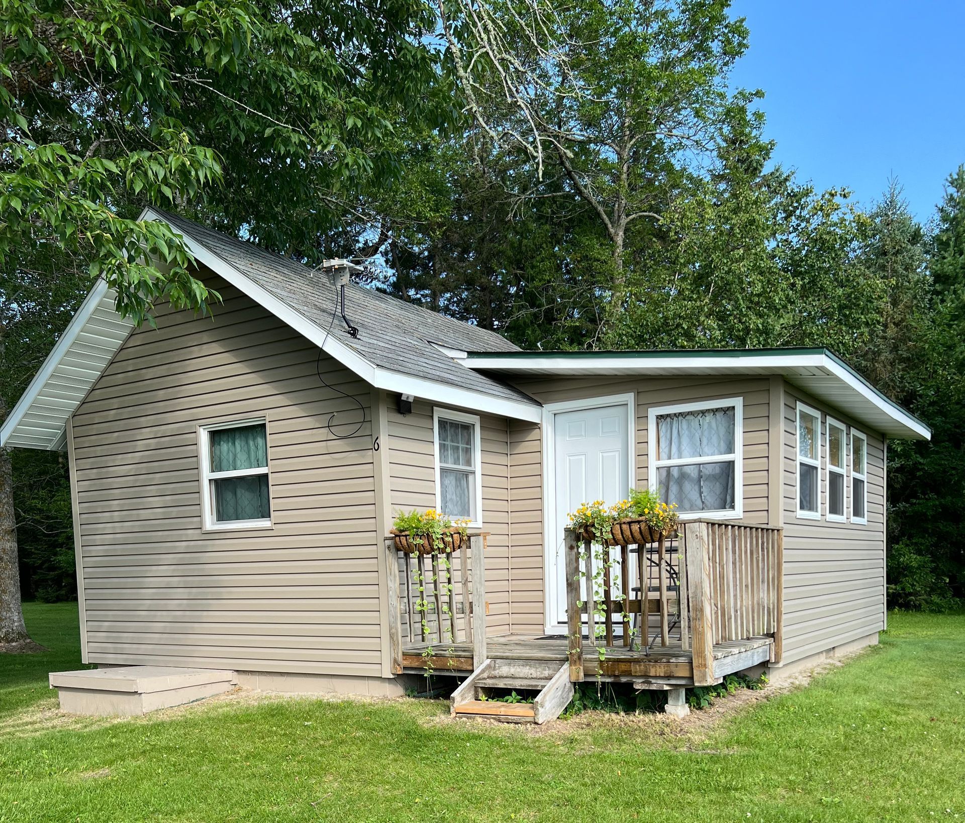 A small house is sitting in the middle of a lush green field.