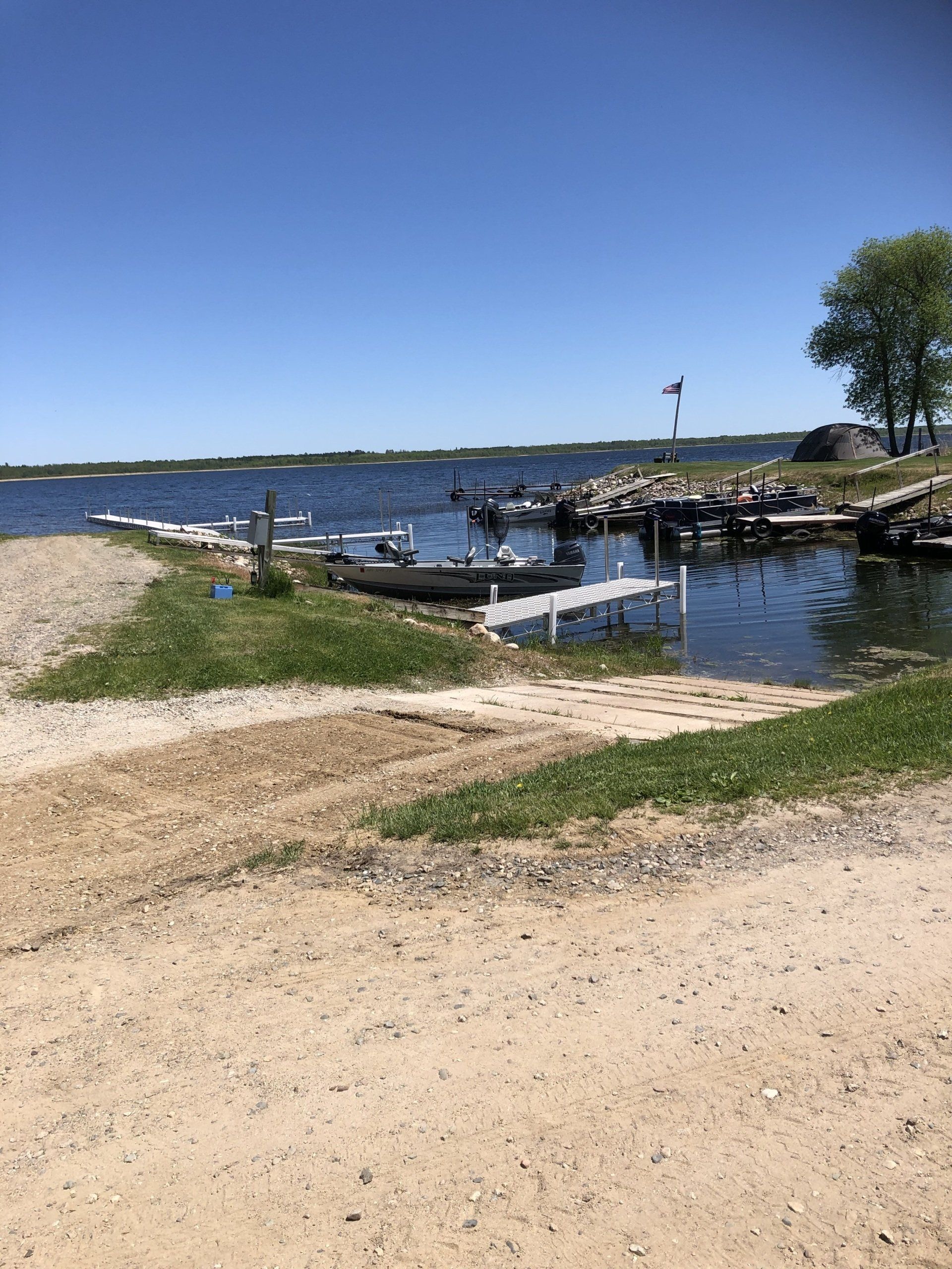A beach with a dock and boats in the water.