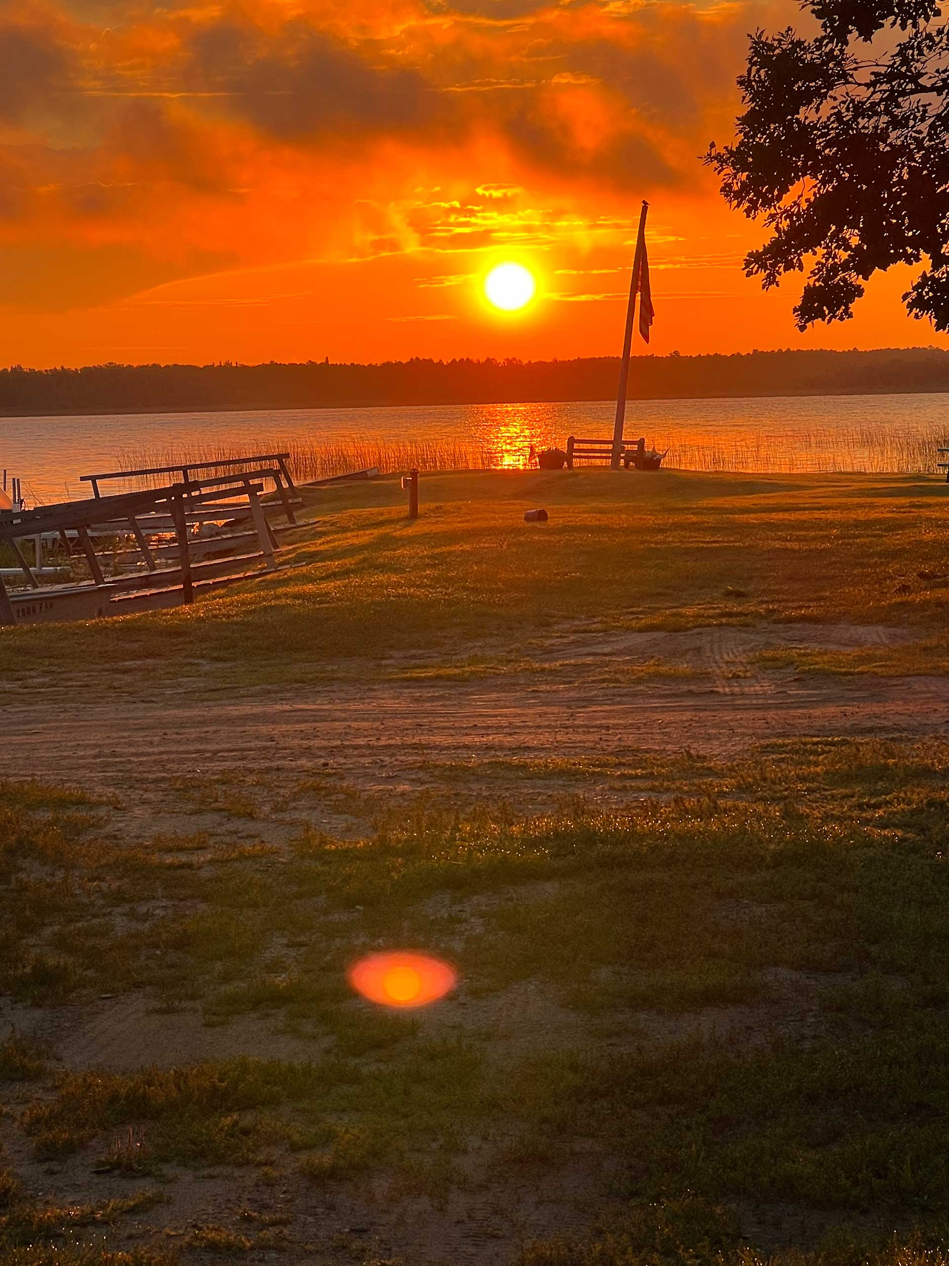 A sunset over a body of water with a flag in the foreground