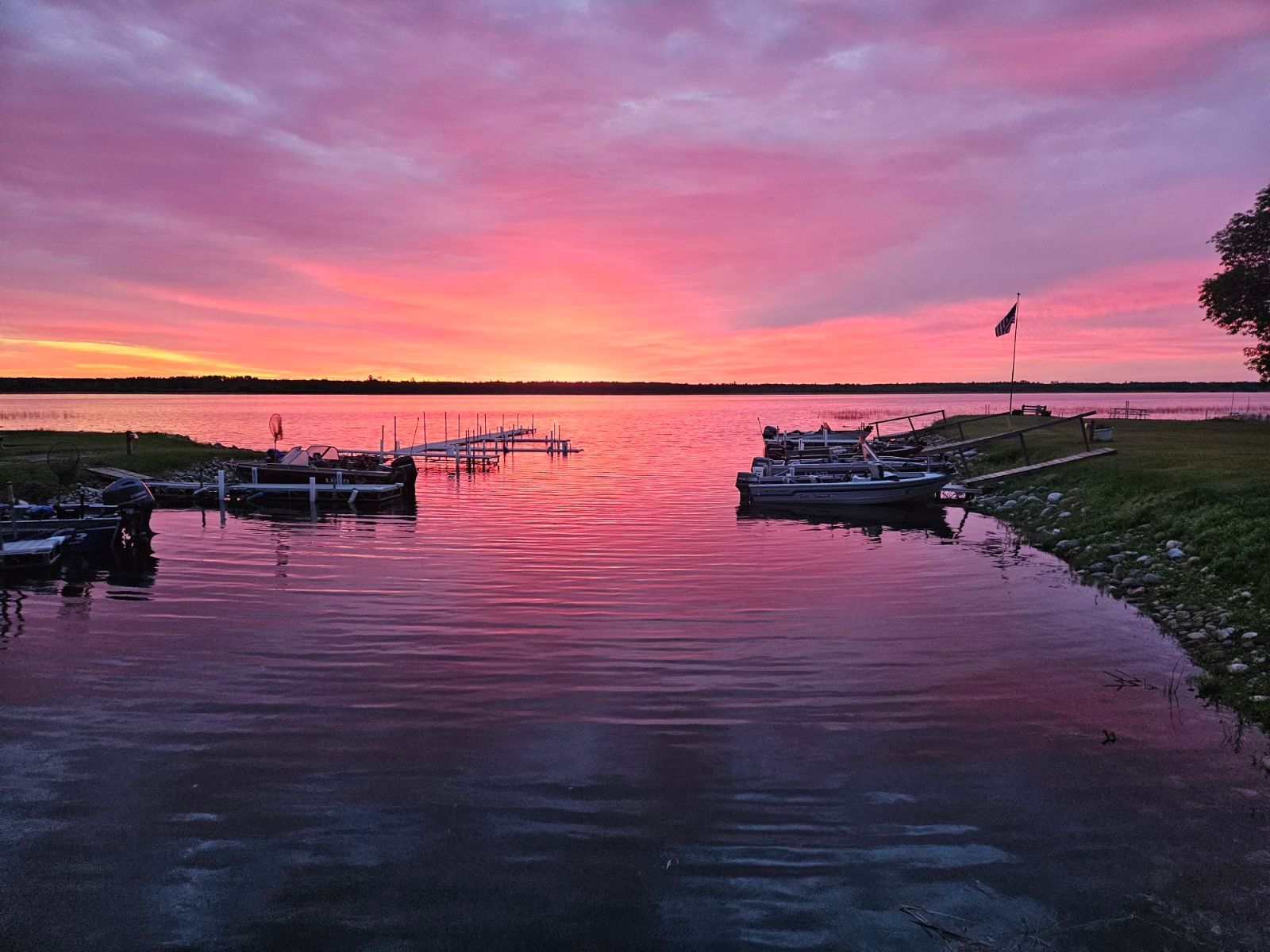 A sunset over a lake with boats docked at a dock.