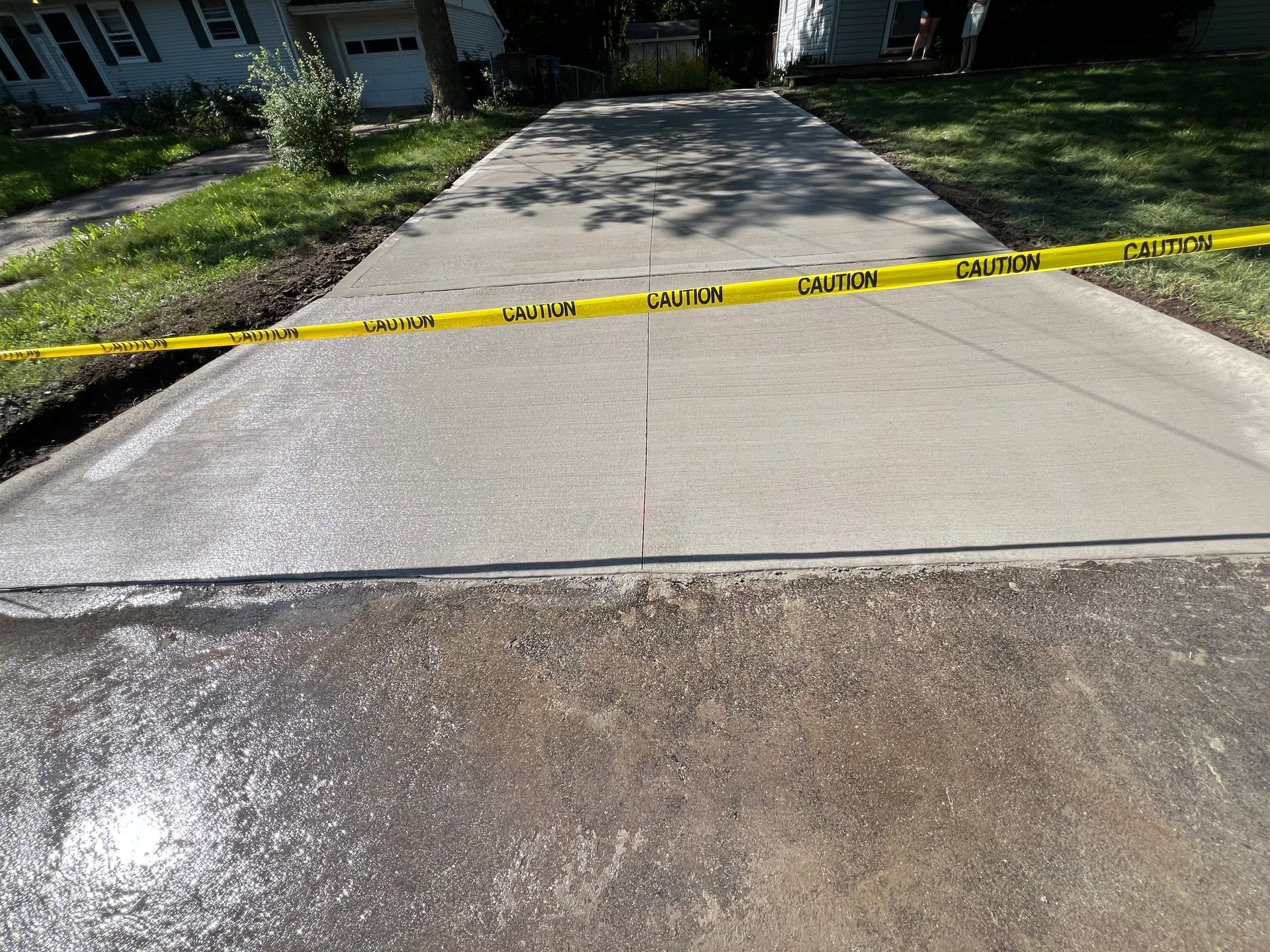 a concrete driveway with a yellow caution tape around it