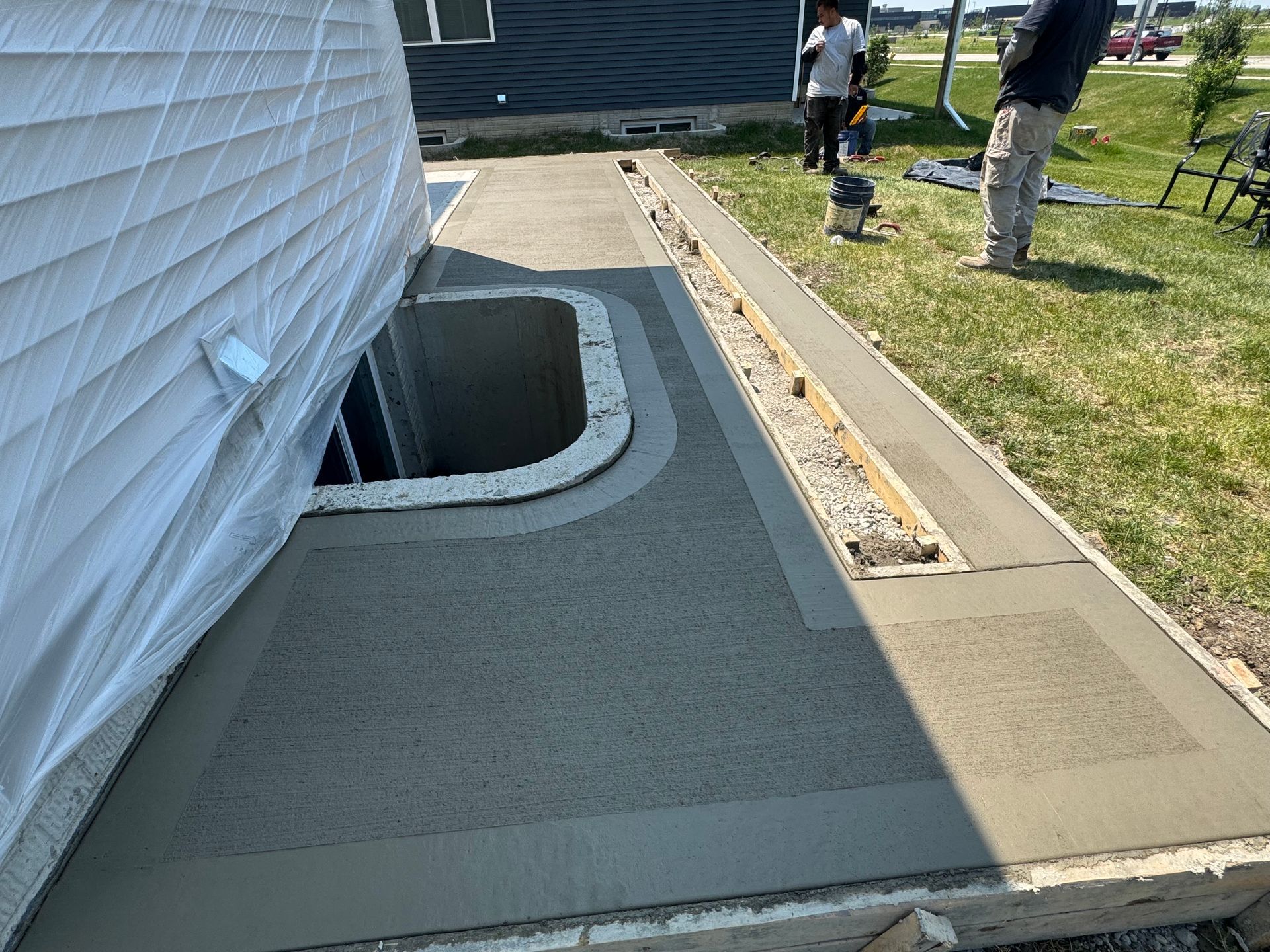 a concrete patio is being built around the basement egress window