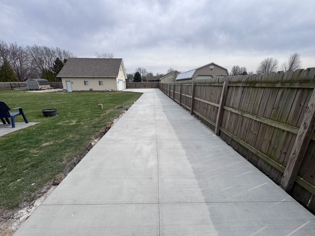 Concrete driveway beside wooden fence leading to houses on a cloudy day