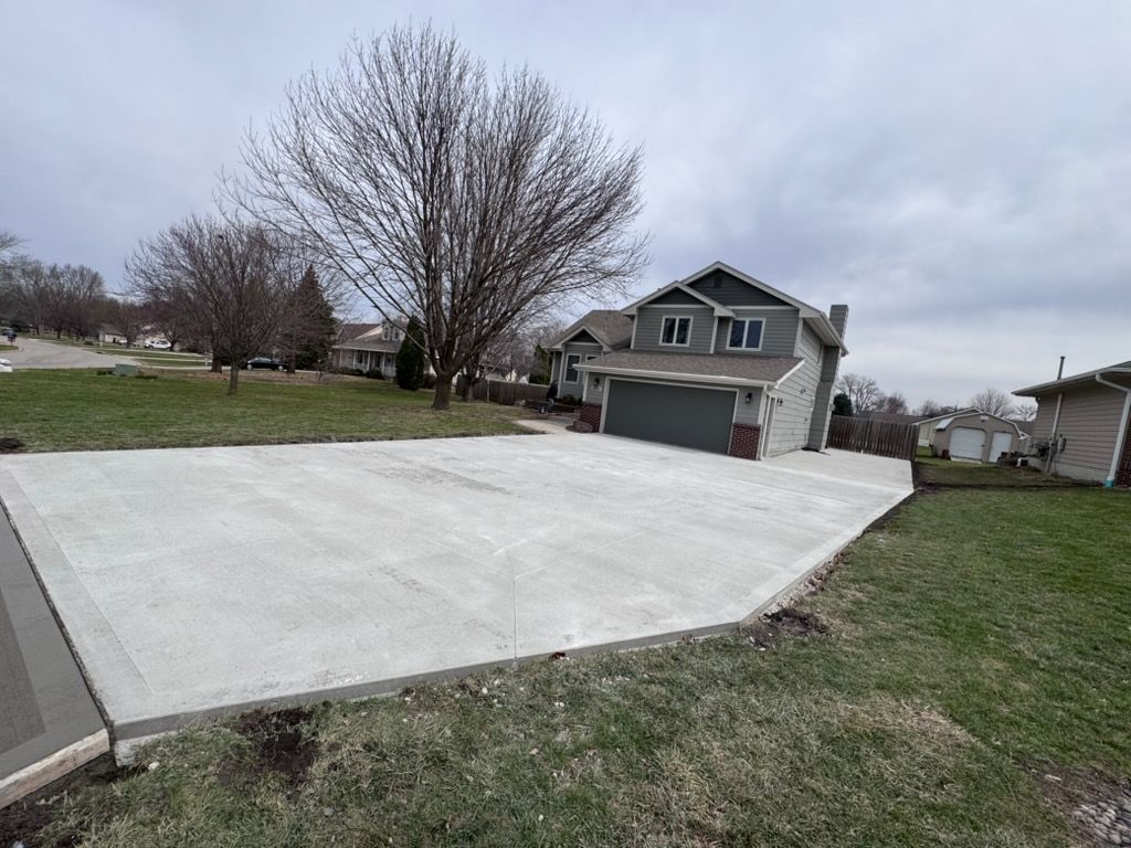 Fresh concrete driveway and walkway beside a suburban house on a cloudy day