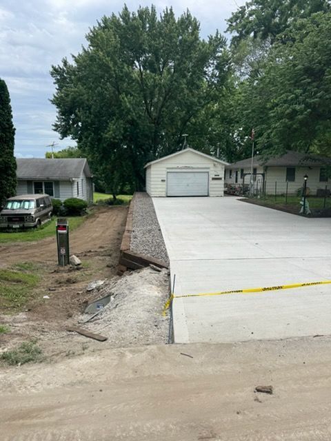 New concrete driveway leading to a garage in a suburban neighborhood, with yellow caution tape nearby