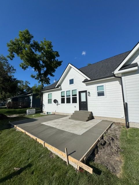White house with a new concrete patio and front steps under a clear blue sky