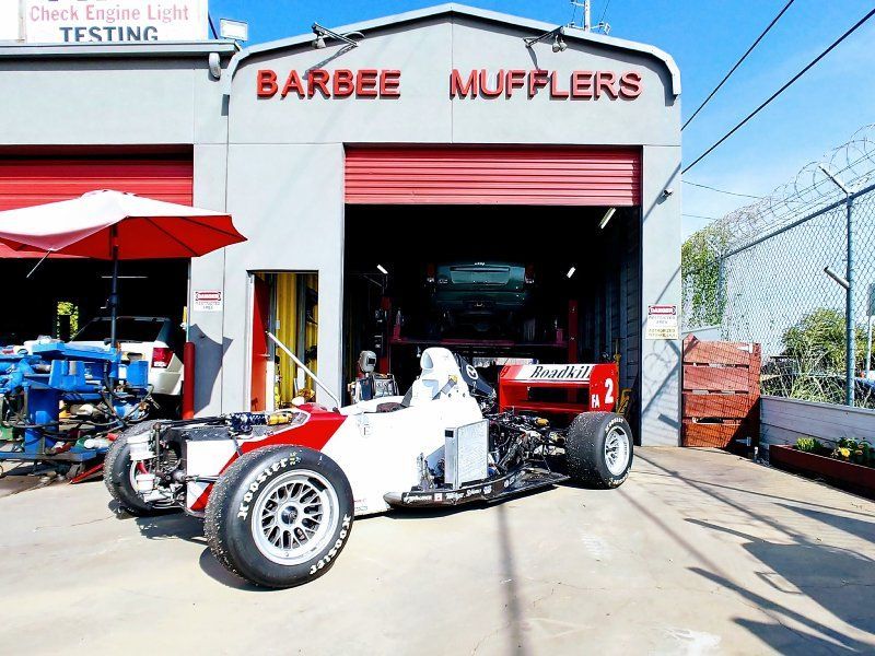 A race car is parked in front of barbee mufflers
