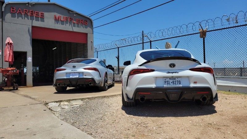 Two sports cars are parked in front of a garage.
